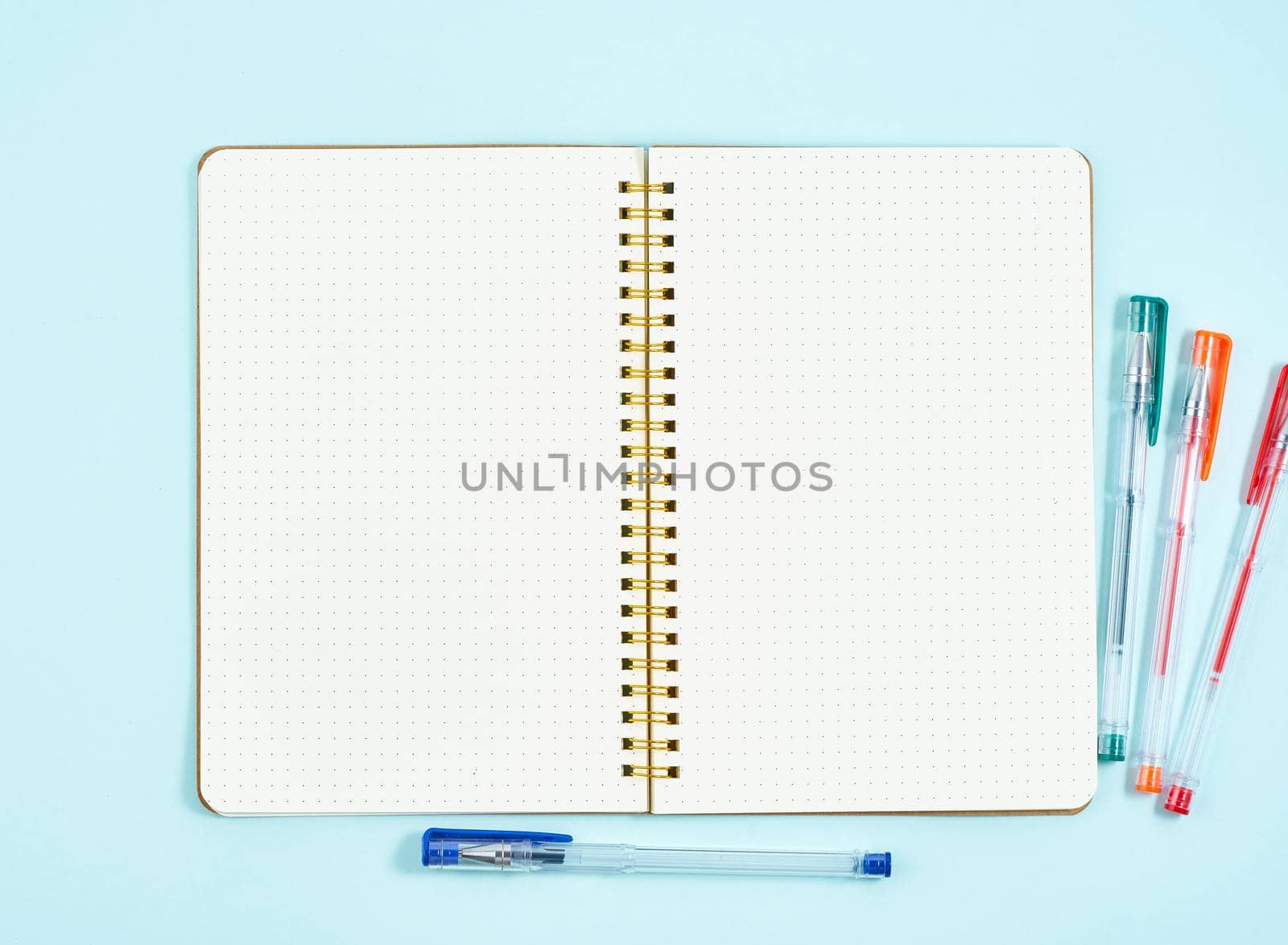 Blank notepad page in bullet journal on blue office desktop. Top view of modern bright table with notebook. Mock up, copy space by NataBene