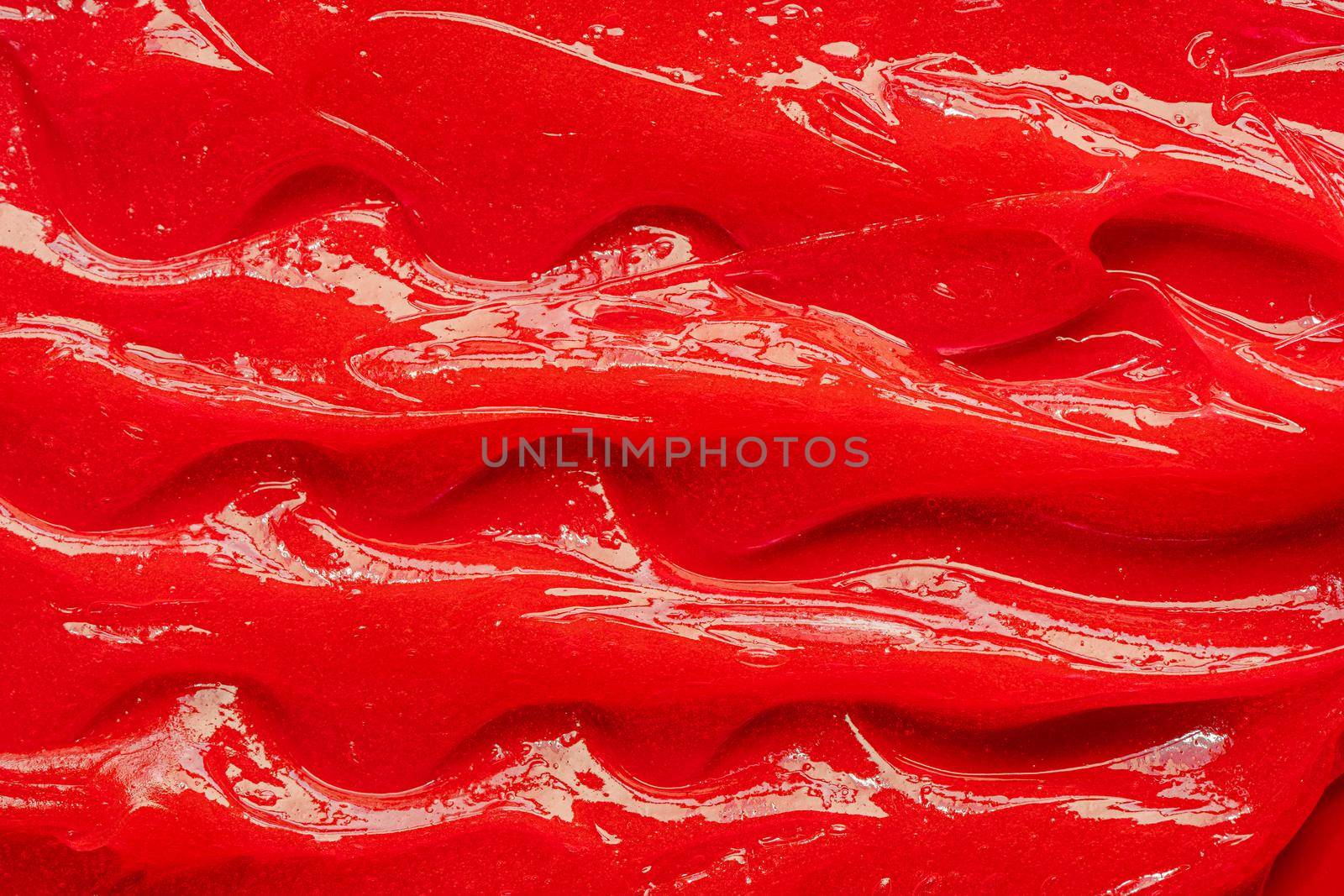 Red gel texture. Cosmetic clear liquid cream smudge. Skin care product sample closeup. Toothpaste or wax by photolime