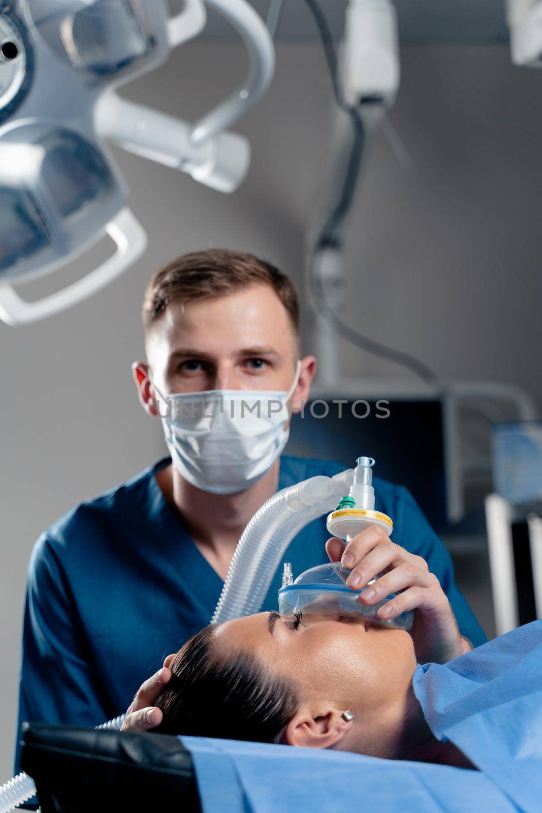Anesthesiologist making ingalation anesthesia for patient. Doctor puts a mask on the patient before starting operation.