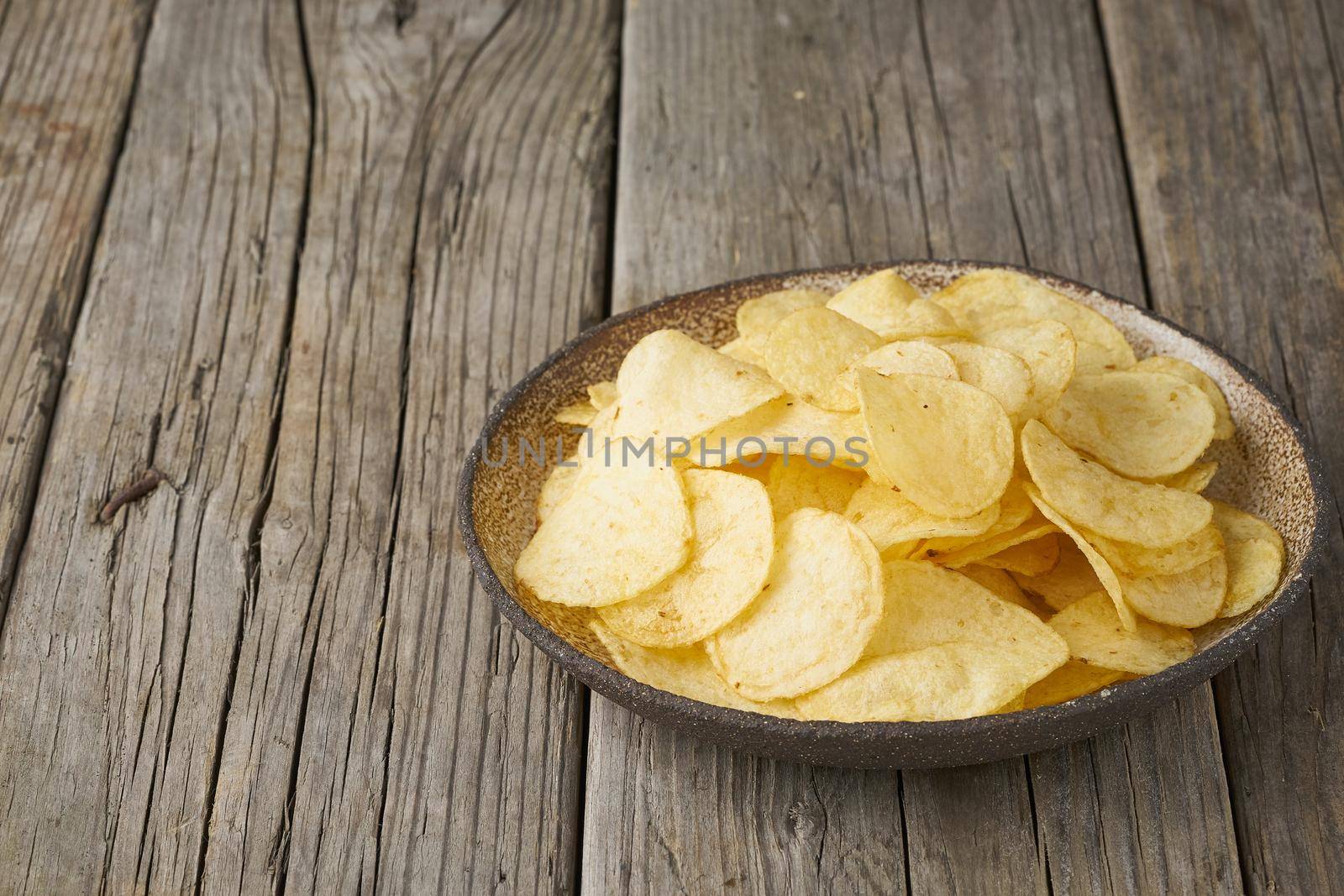 crisp in bowl, wooden background, closeup, copy space