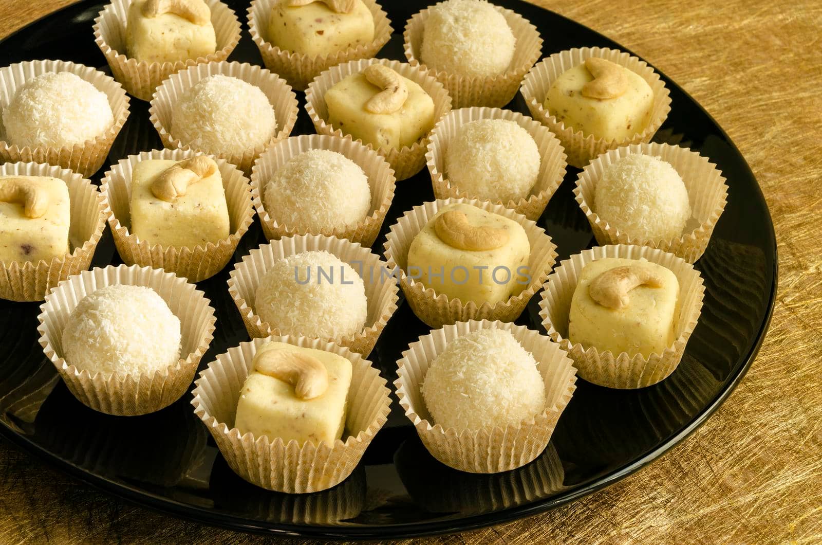 White chocolate homemade truffles with cashew on black plate From series elegant desserts