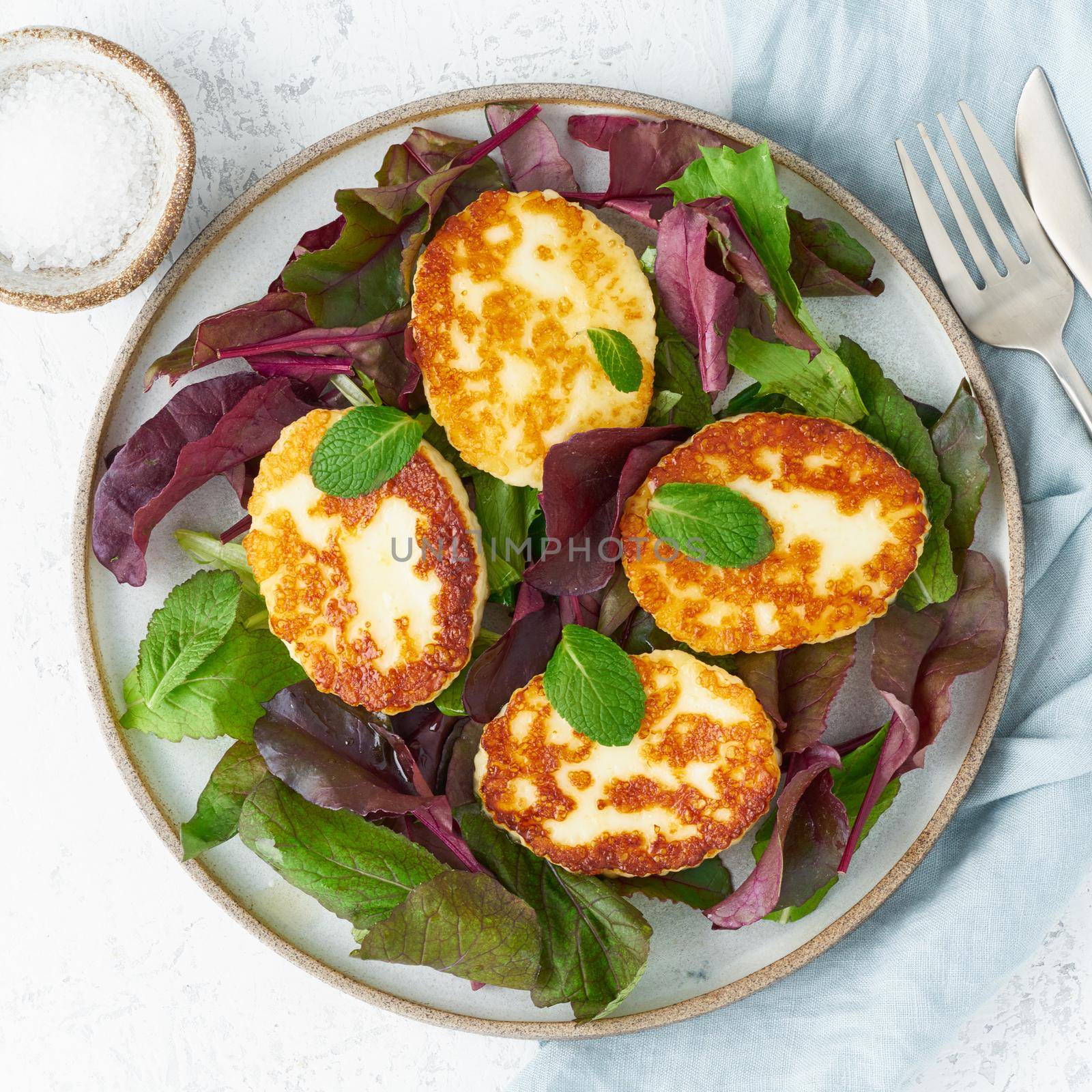 Cyprus fried halloumi with salad mix, beet tops. Lchf, pegan, fodmap, paleo, scd, keto, ketogenic diet. Balanced food, clean eating recipe. Top view, a white background