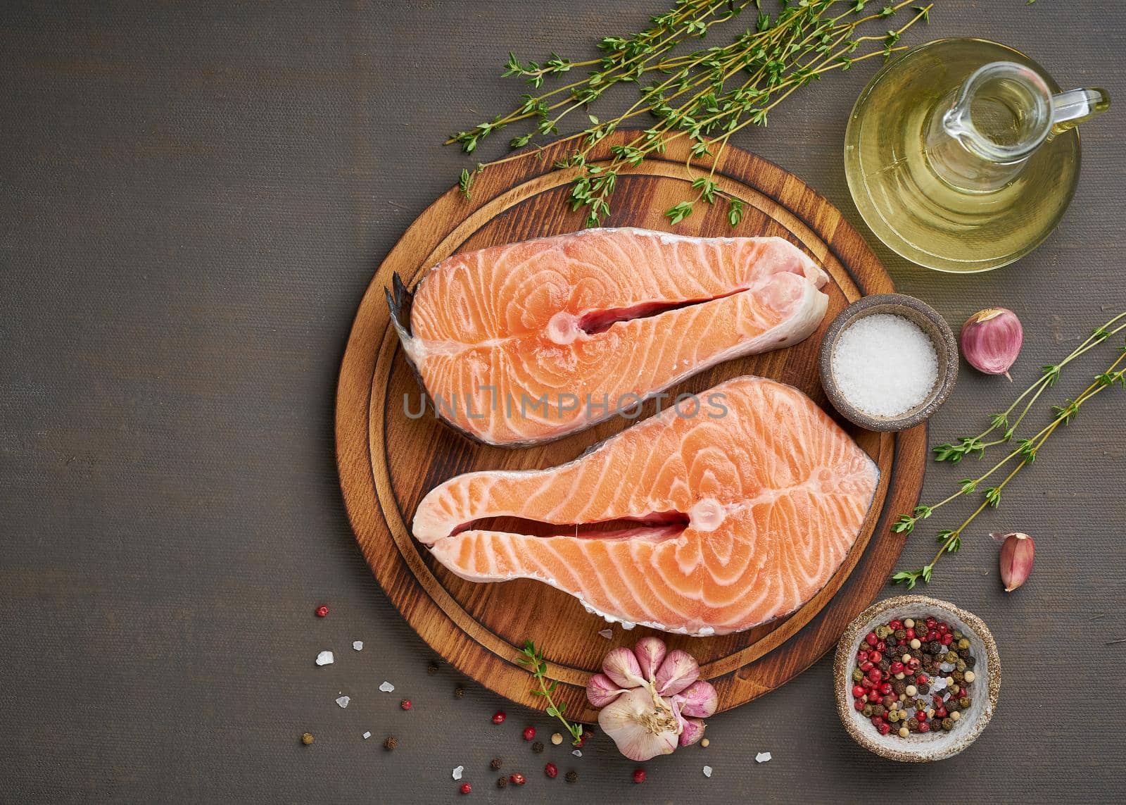 Two salmon steaks, top view, copy space. Fish fillet, large sliced portions on chopping board on dark table.