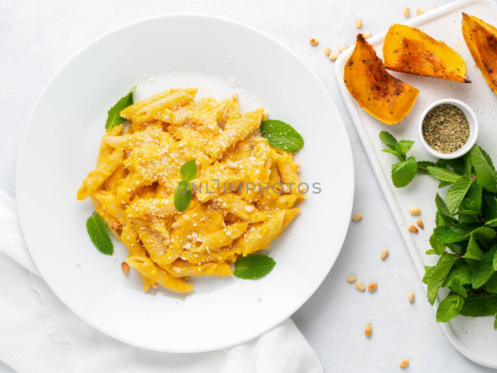 Pumpkin pasta penne with creamy sauce of baked squash on white background, top view