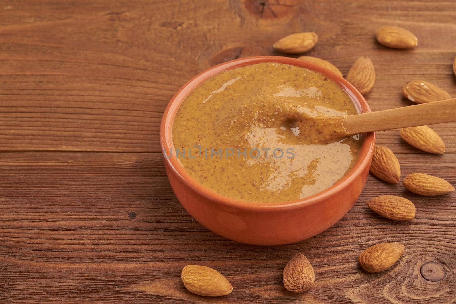 almond butter, raw food paste made from grinding almonds into nut butter, crunchy and stir, dark brown wooden table, copy space