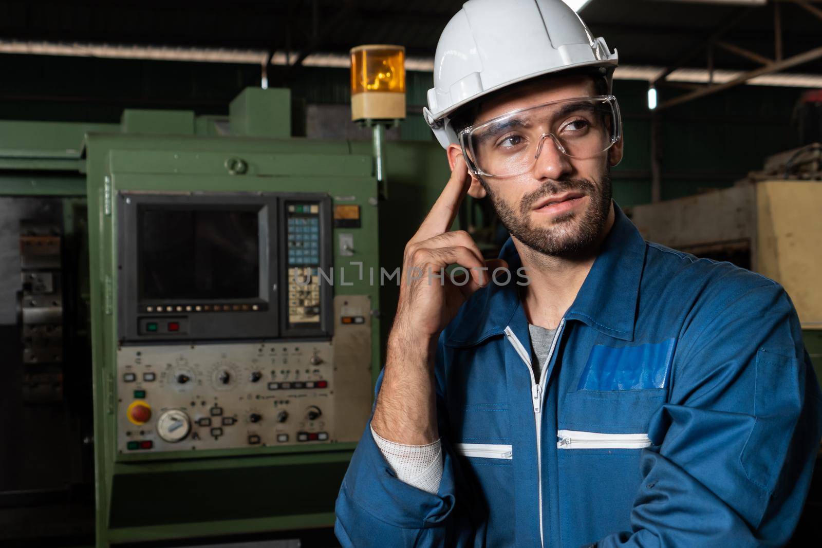 Skillful factory engineer or worker portrait while thinking and looking forward . Industrial people and manufacturing labor concept .