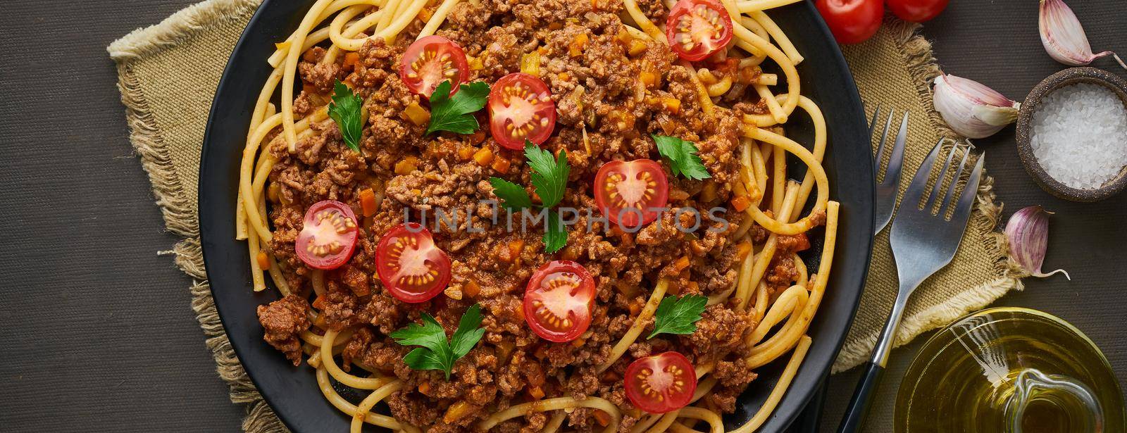 mediterranean pasta bolognese bucatini with mincemeat, tomatoes, carrot and basil leaves