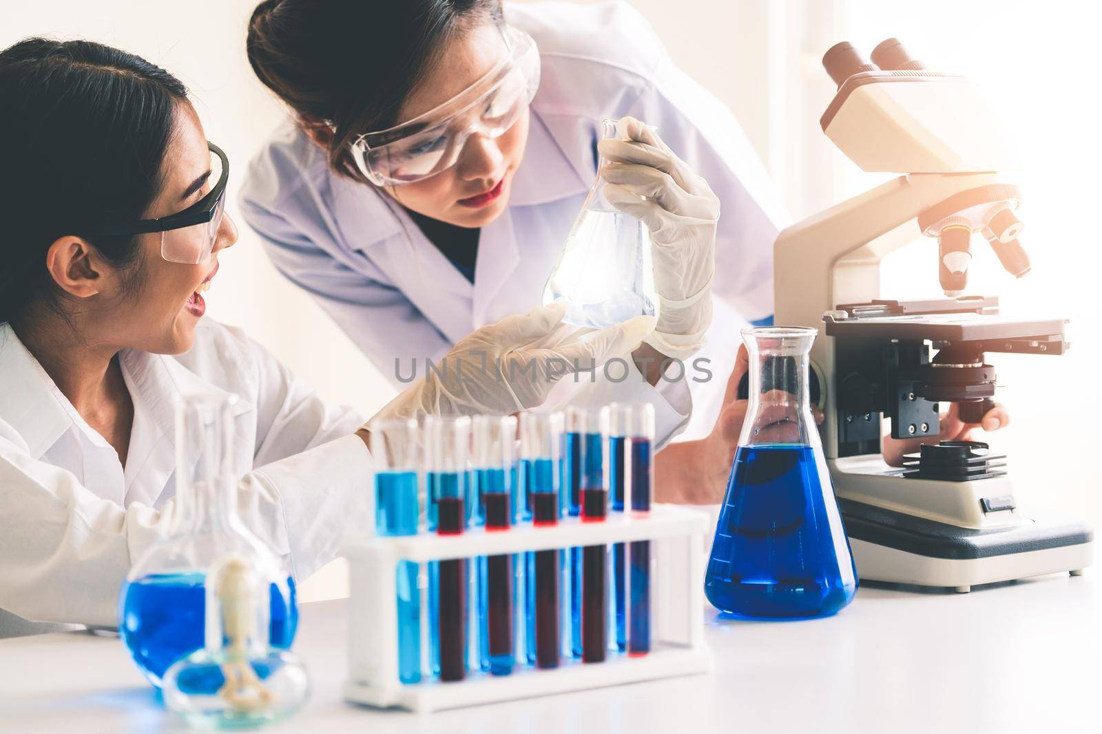 Group of scientists wearing lab coat working in laboratory while examining biochemistry sample in test tube and scientific instruments. Science technology research and development study concept.