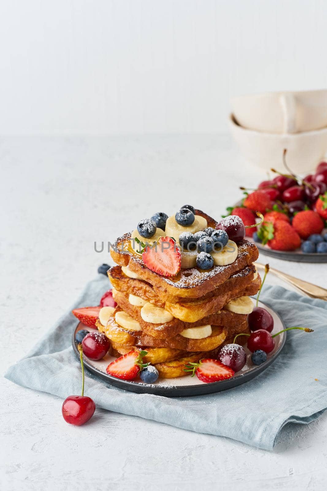 French toasts with berries and banana, brioche breakfast, white background vertical closeup by NataBene