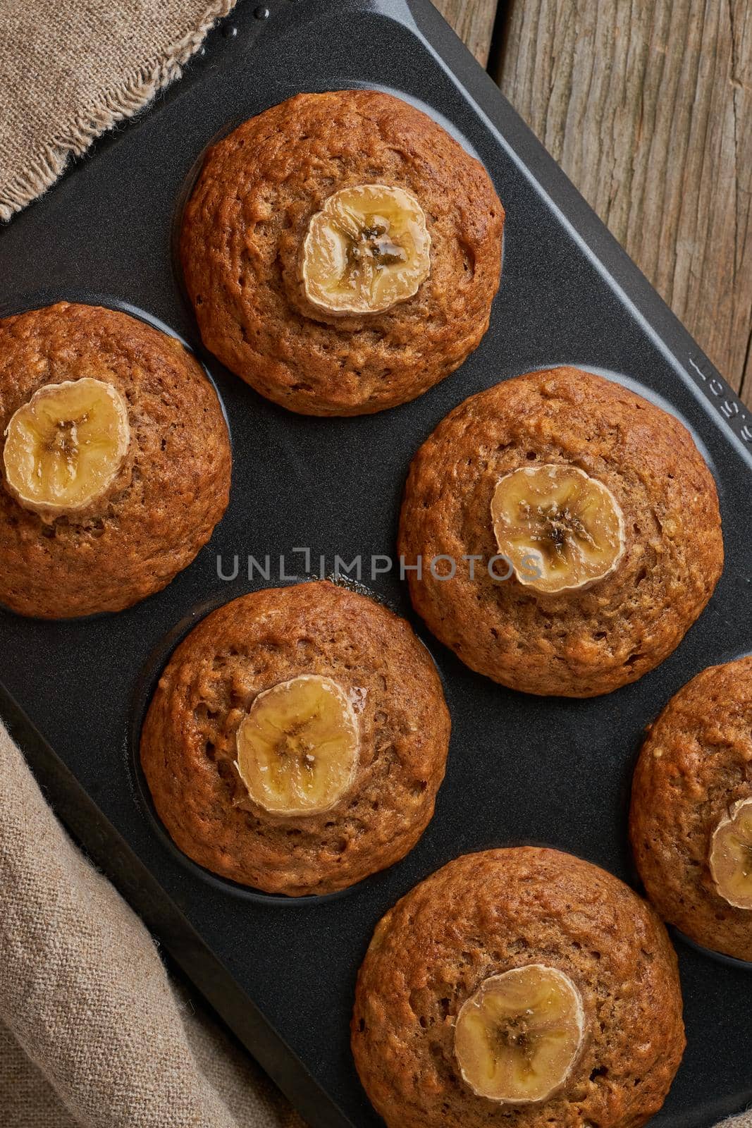 Banana muffin in tray, top view, copy space. Cupcakes on old linen napkin, by NataBene