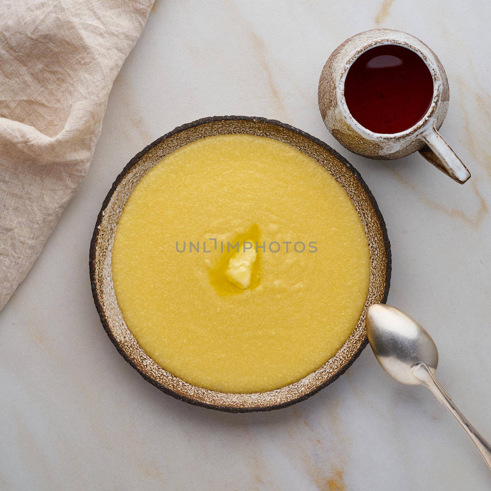 porridge polenta with butter and cup of tea, white background pastel top view