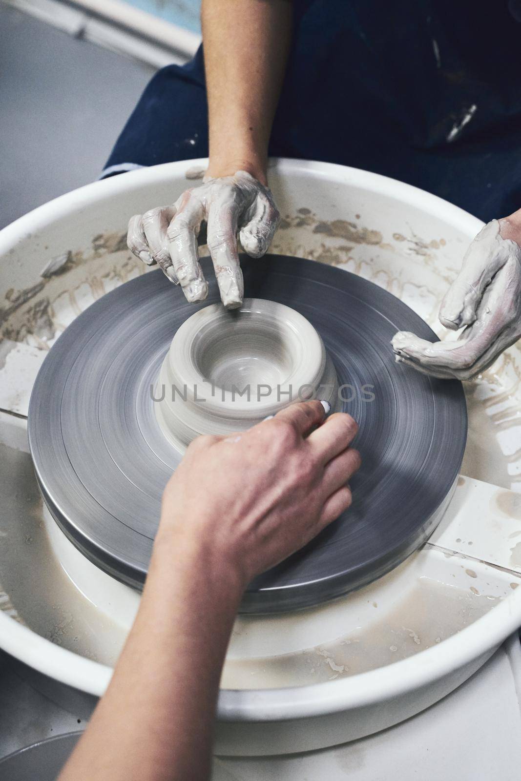 Woman making ceramic pottery, four hands close-up, focus on a potters, palms with pottery, concept for workshop and master class. Creative hobby concept. Earn extra money, side hustle, vertical