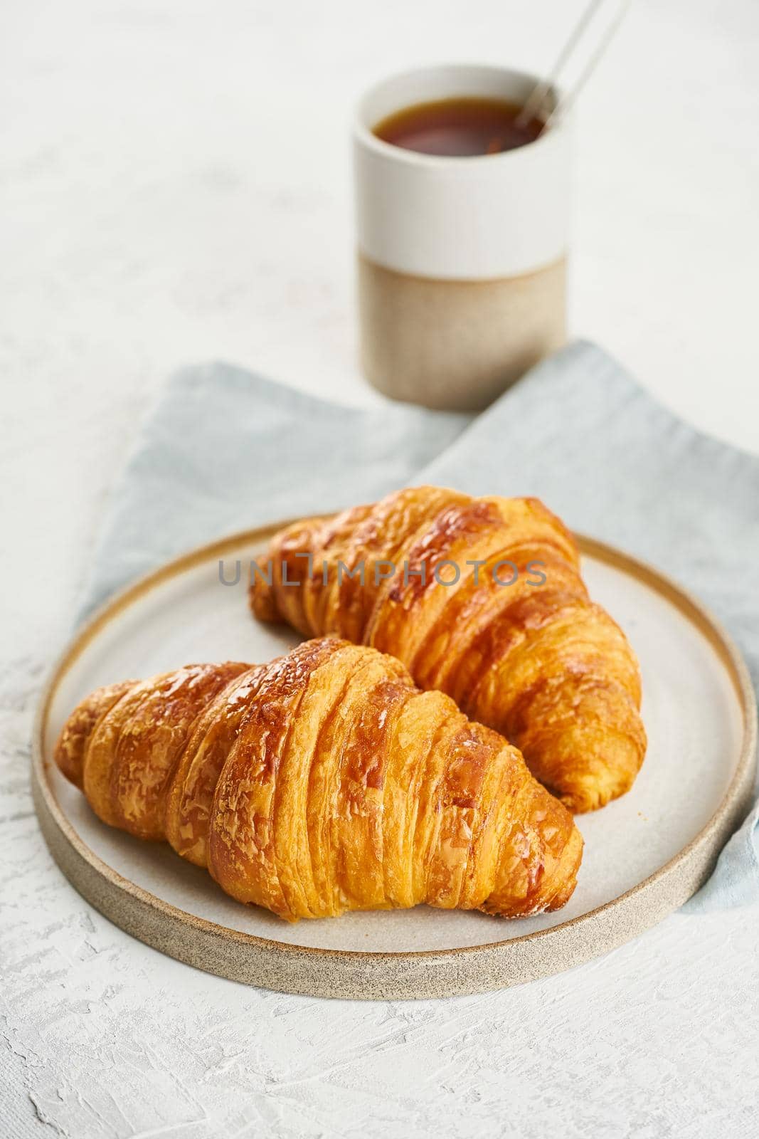 Two delicious croissants on plate and hot drink in mug. Morning French breakfast by NataBene
