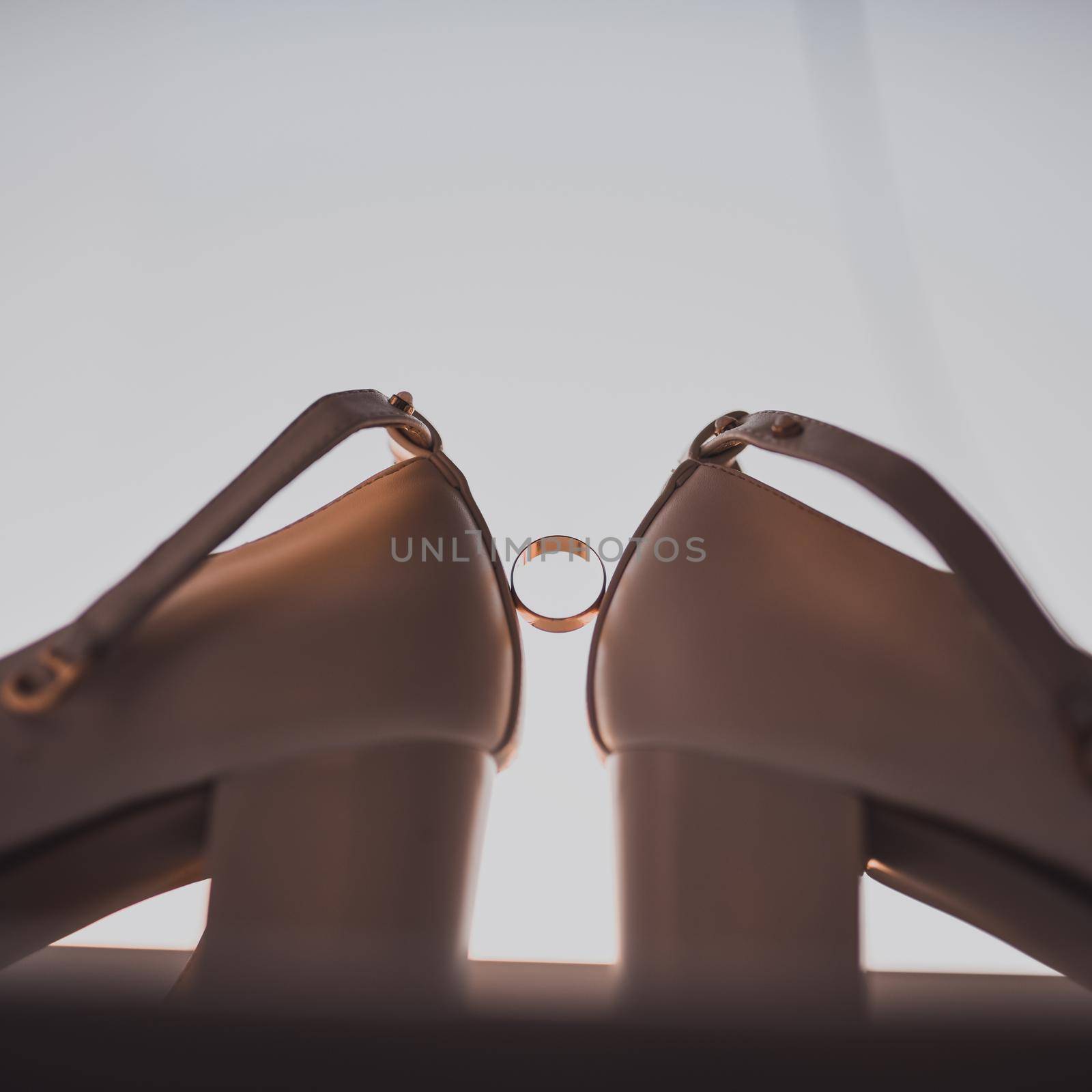 a ring between two women's high heel shoes. Morning of the bride