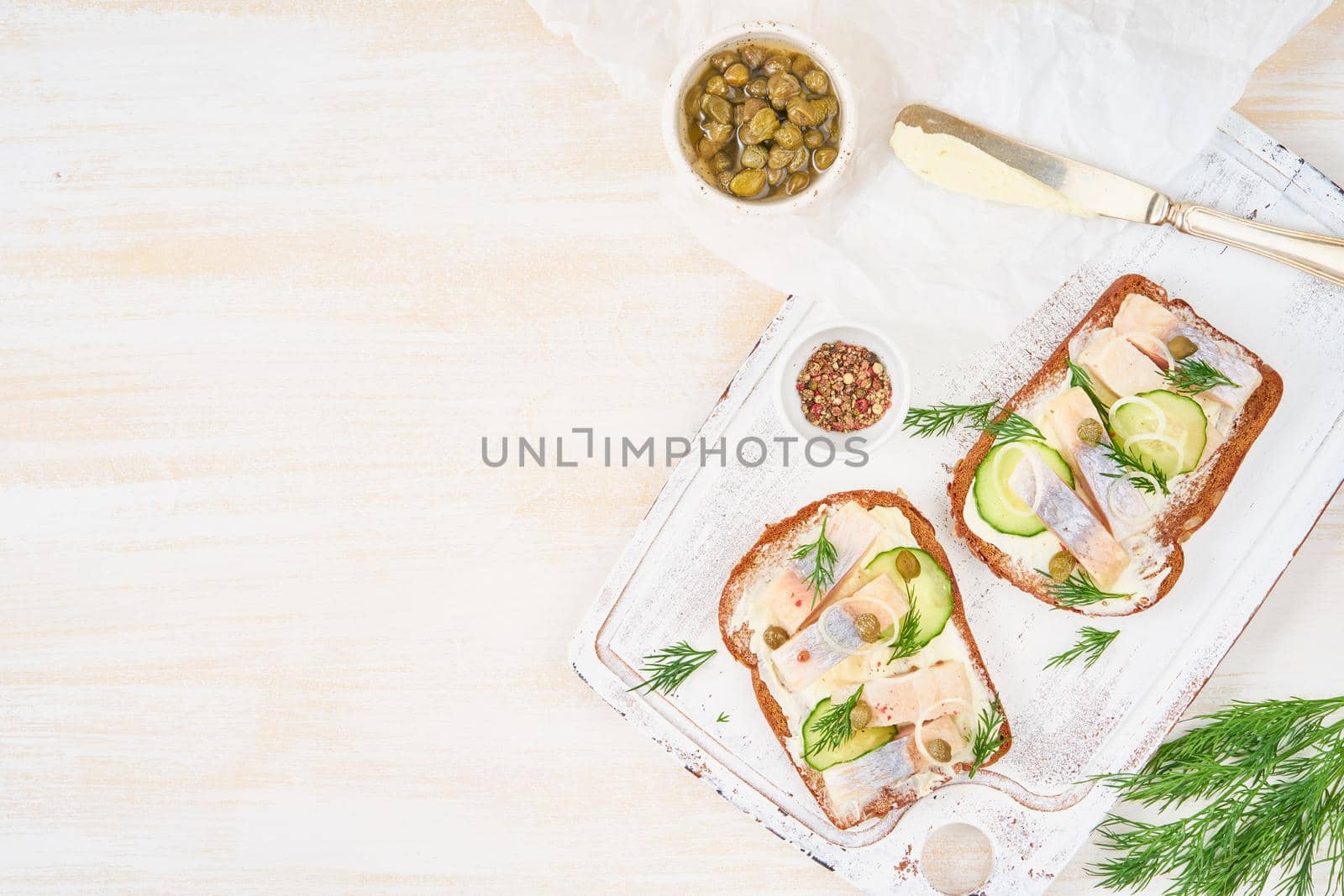 Herring smorrebrod - traditional Danish sandwiches. Black rye bread with herring on white wooden board, top view, copy space