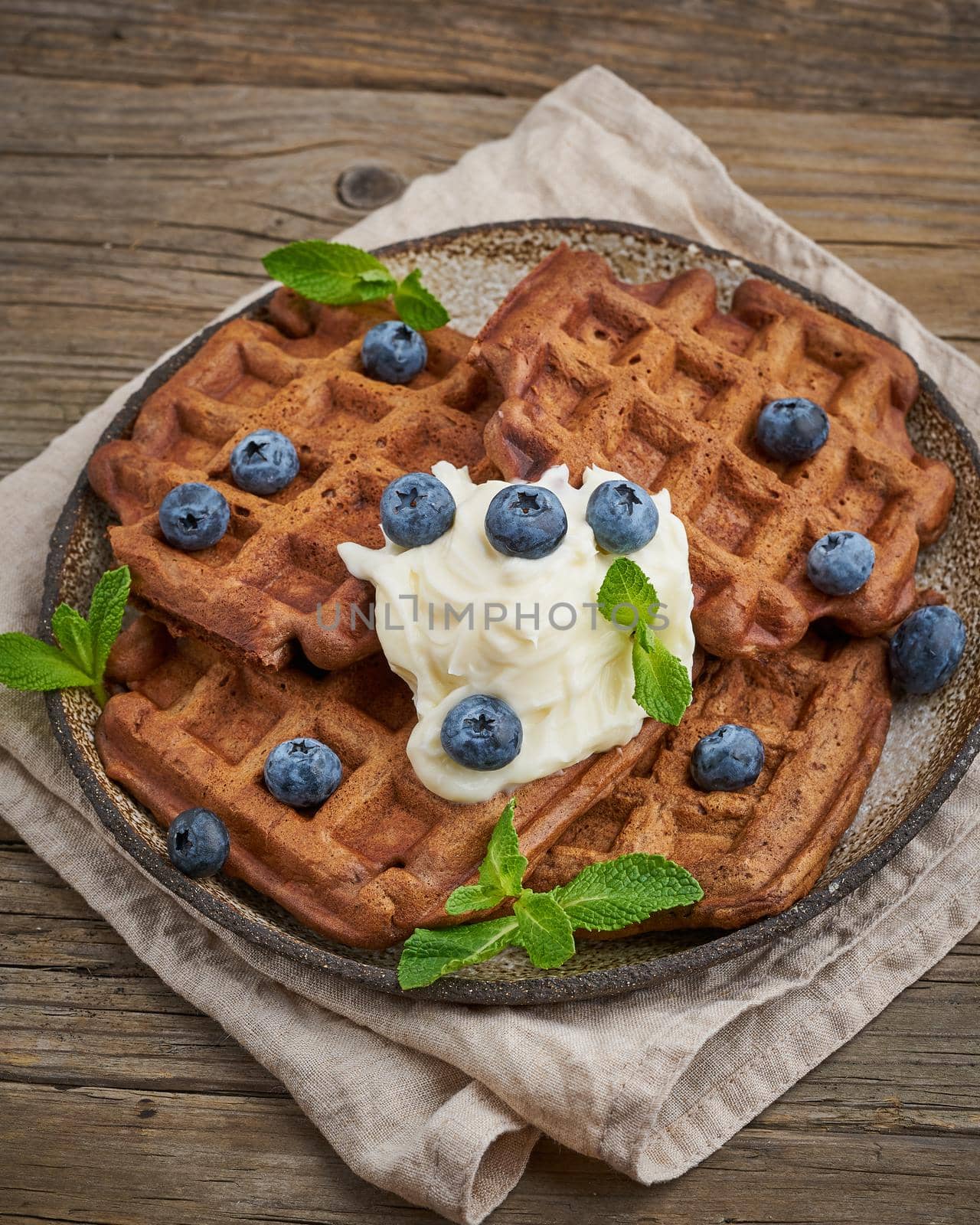 Chocolate banana waffles with blueberries, on dark wooden the old table. Side view, vertical