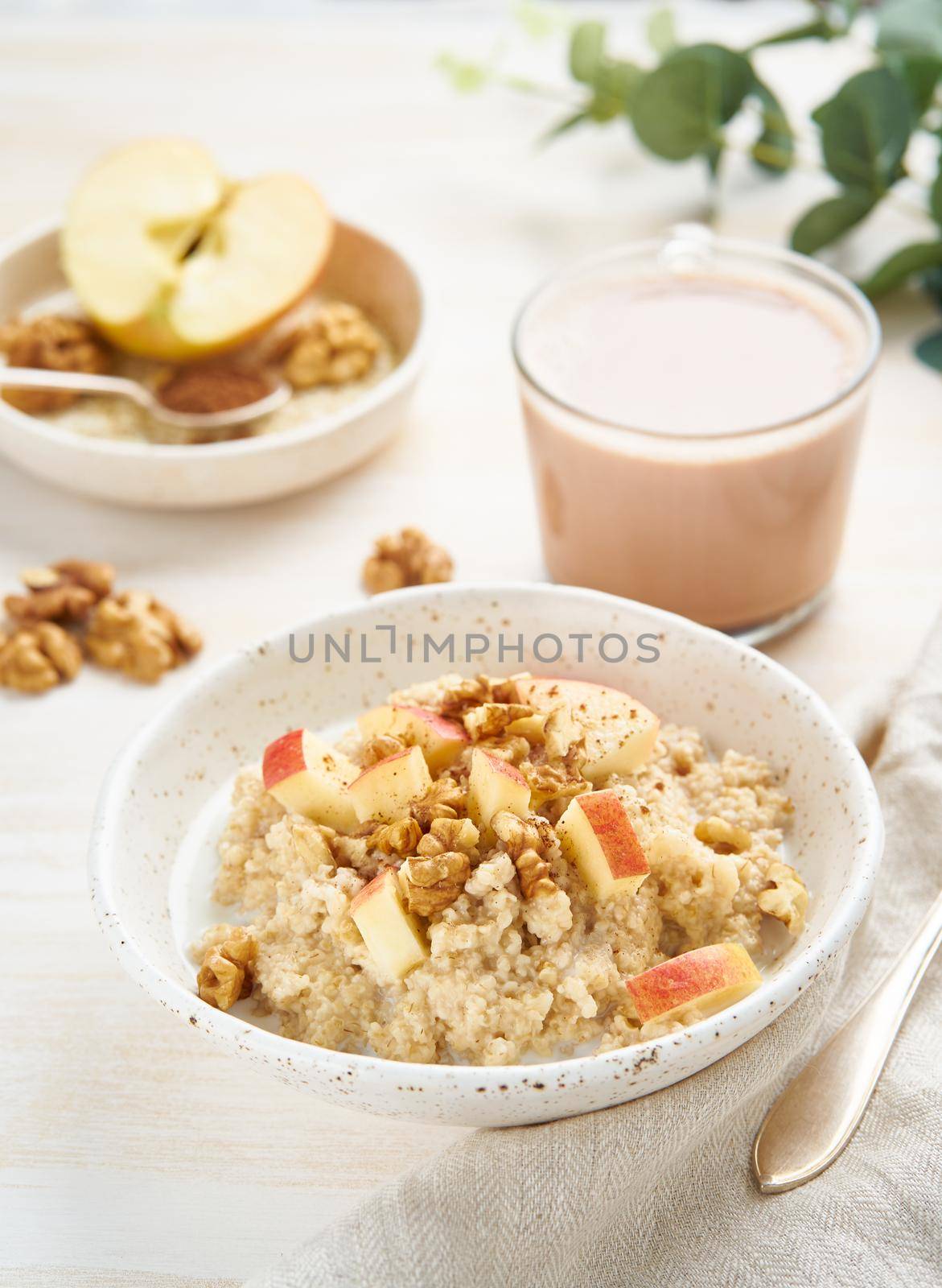 Oatmeal with apple, nuts, honey and cup of chocolate on white by NataBene