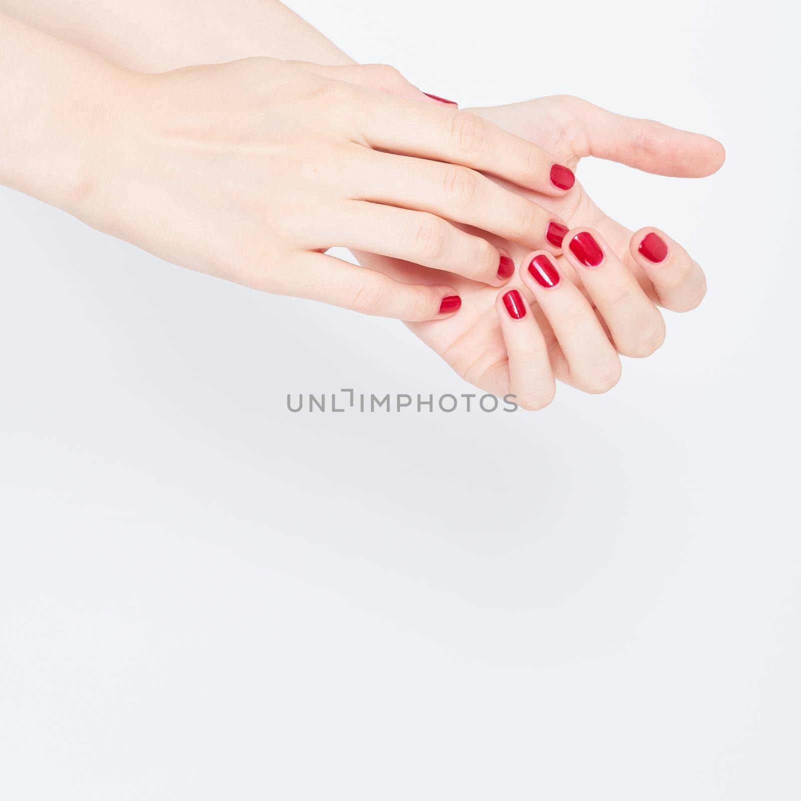woman showing manicures hands with red nail polish on white background copy space by NataBene