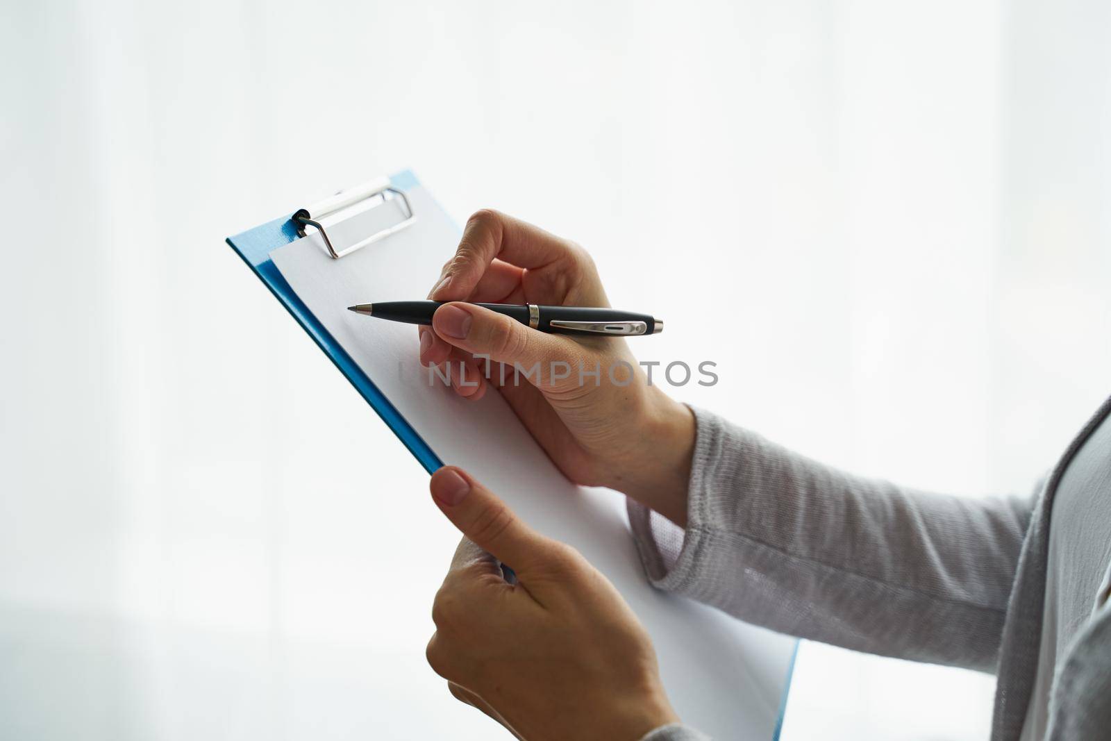 woman holding clipboard and writing on it, concept of work with documents and information