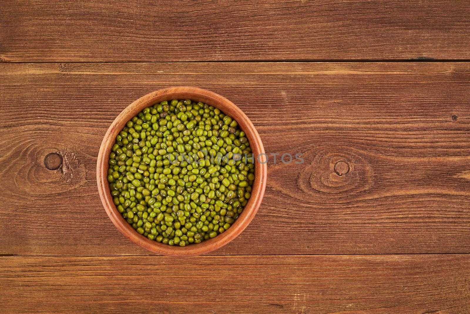 Mung beans in wooden bowl on brown background, top view, copy space, close up