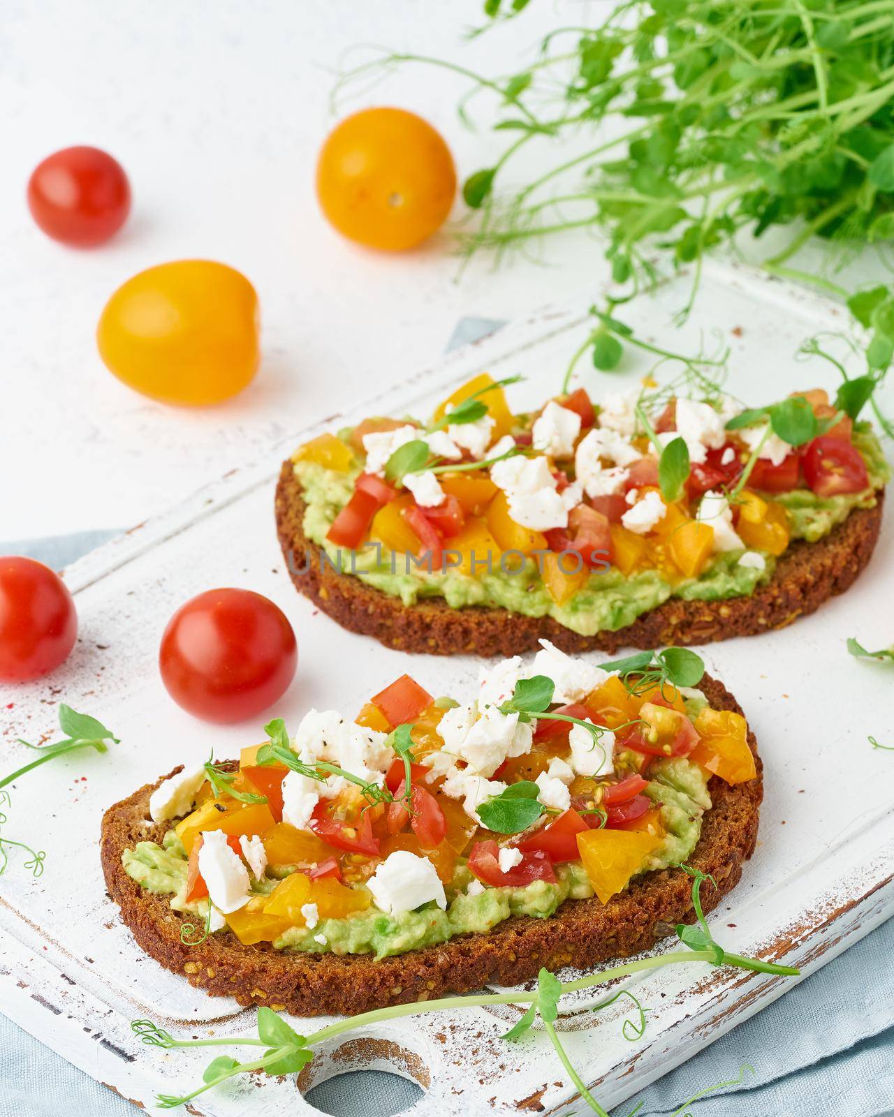 avocado toast with feta and tomatoes, smorrebrod with ricotta, closeup and vertical