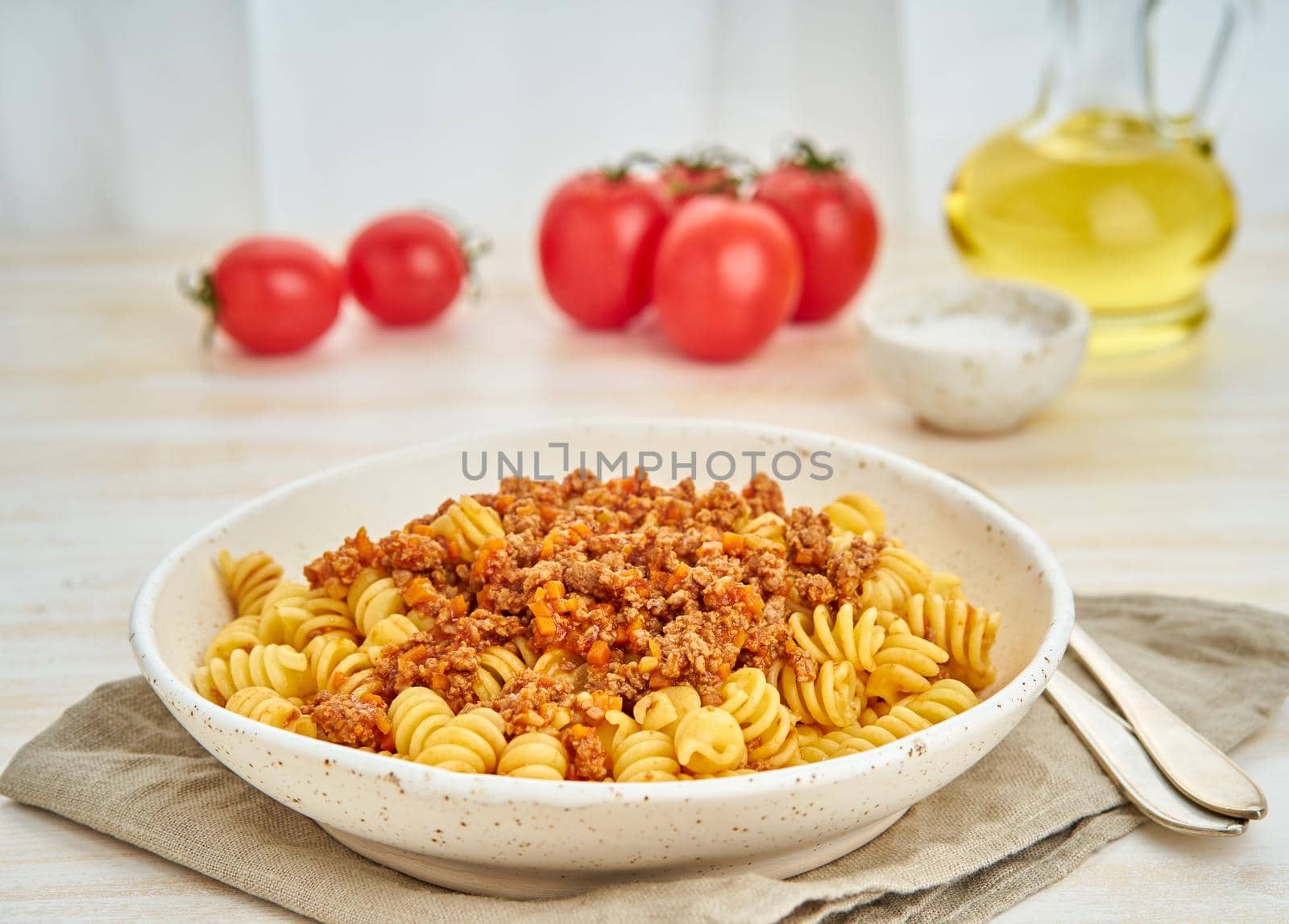 Bolognese pasta. Fusilli with tomato sauce, ground minced beef. Traditional italian cuisine. White wooden table. Side view