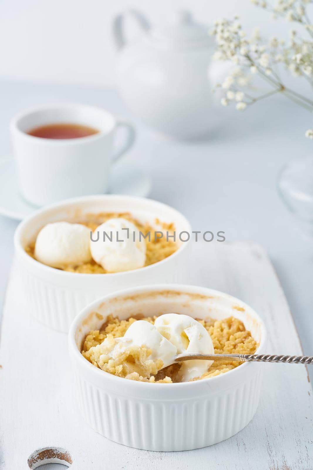 Apple crumble, spoon with ice cream, streusel. Side view, vertical. Morning breakfast.