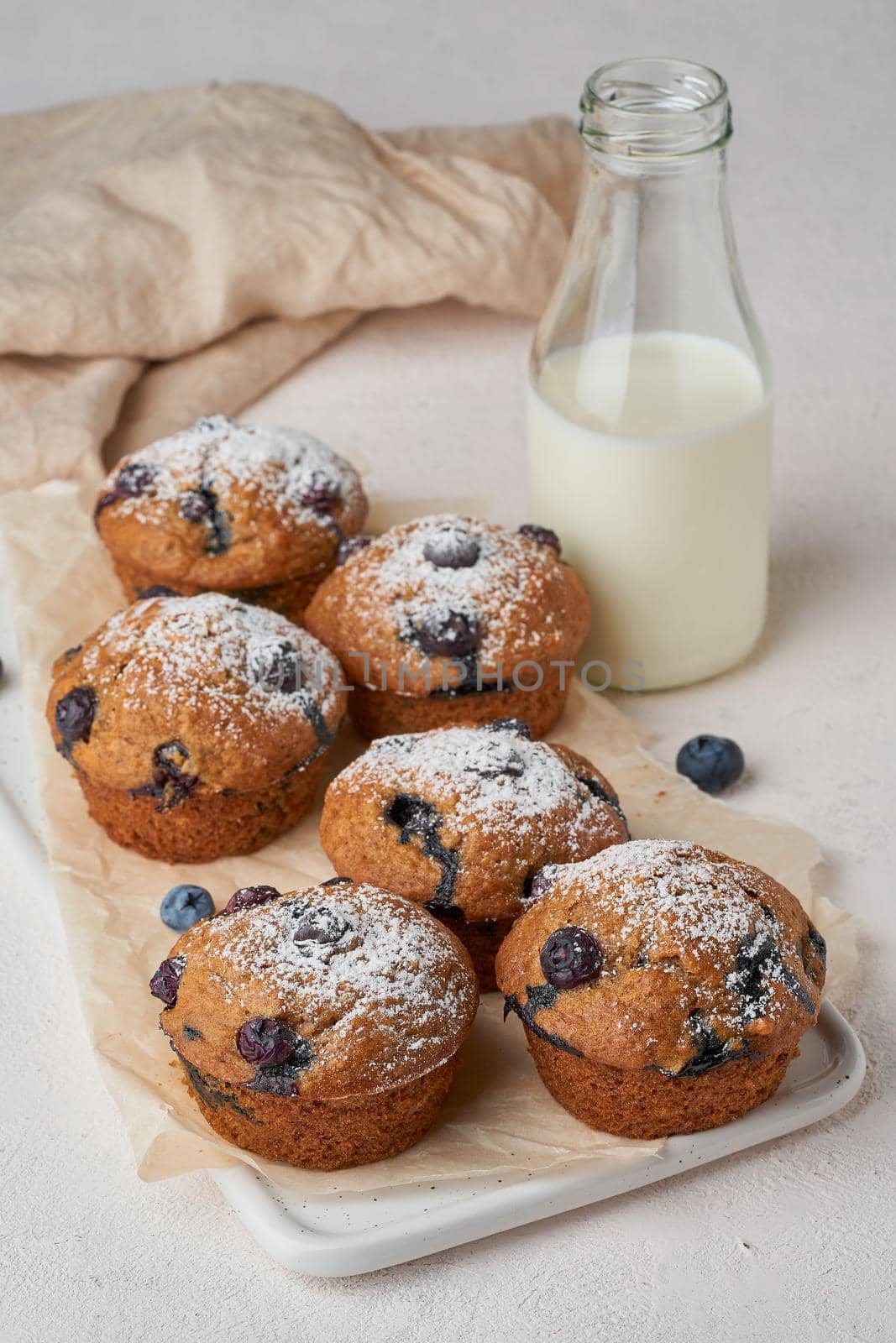 Blueberry muffin, side view, vertical. Cupcakes with berries on a white concrete table, breakfast with cake and milk
