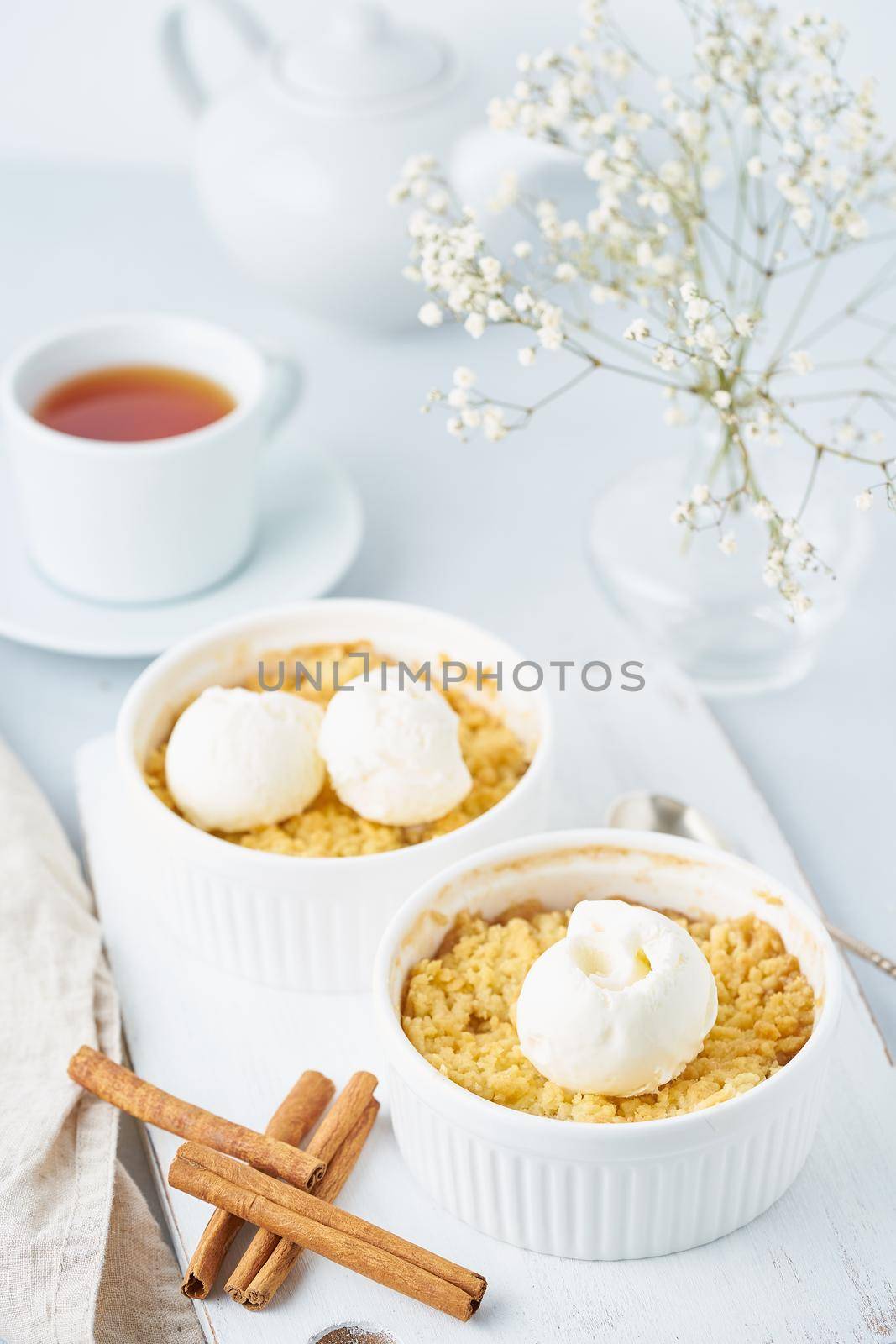 Apple crumble with streusel, tea, cinnamon on a light gray table. Vertical. by NataBene