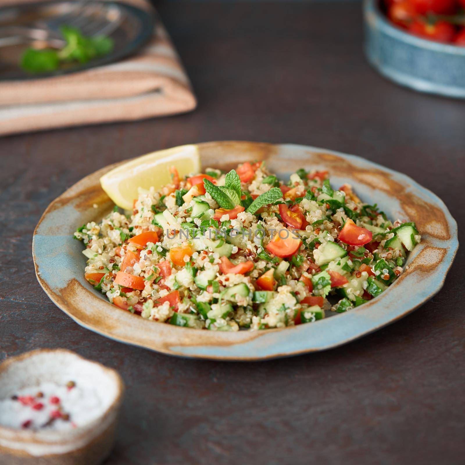 Tabbouleh salad with quinoa. Eastern food with vegetables mix, vegan diet. Side view, old plate