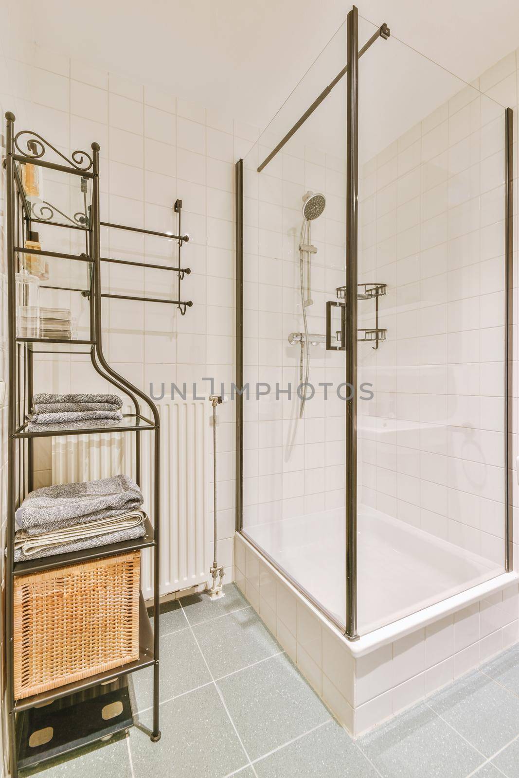 The interior of a bathroom with a glazed shower and shelves for towels in a modern apartment