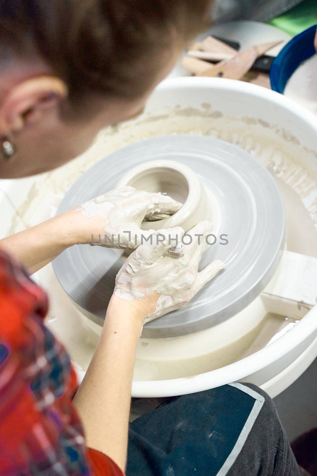 Woman making ceramic pottery on wheel, hands closeup. Concept for woman in freelance, business, creative hobby. Earn extra money, side hustle, vertical