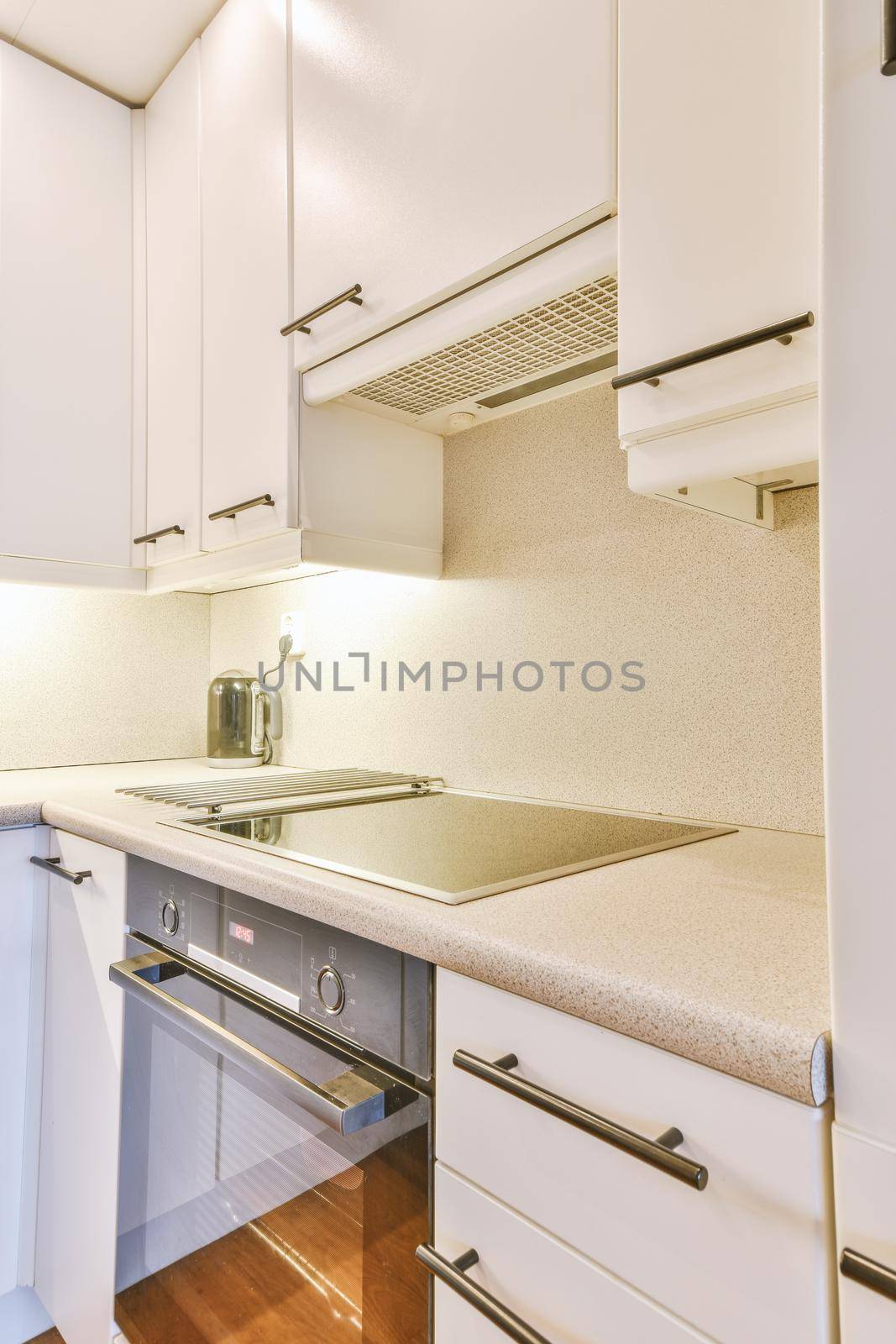 Cozy minimalist kitchen with lots of cabinets in white and modern appliances in a cozy apartment