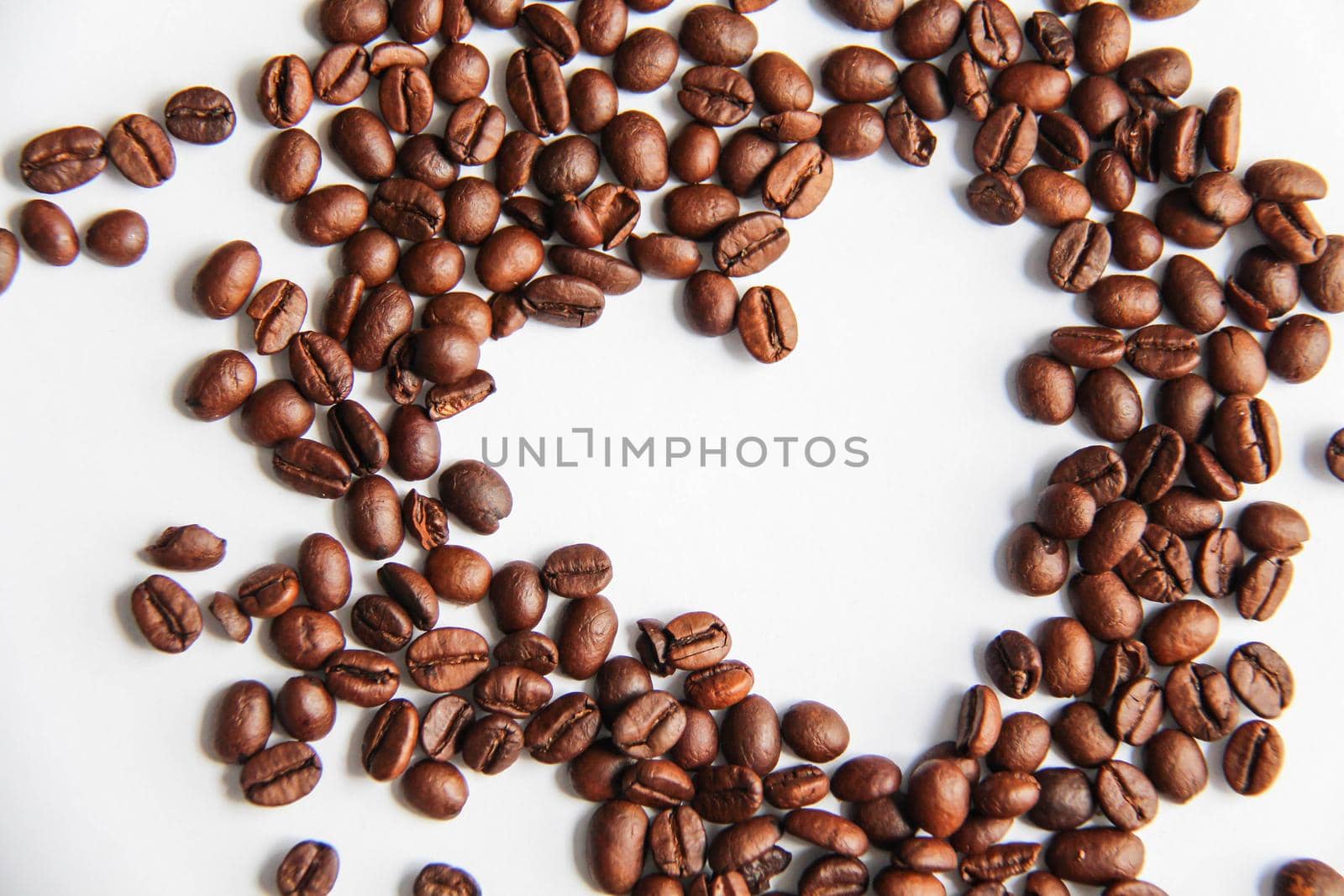 Heart shape roasted coffee beans with coffee beans background isolated on white.