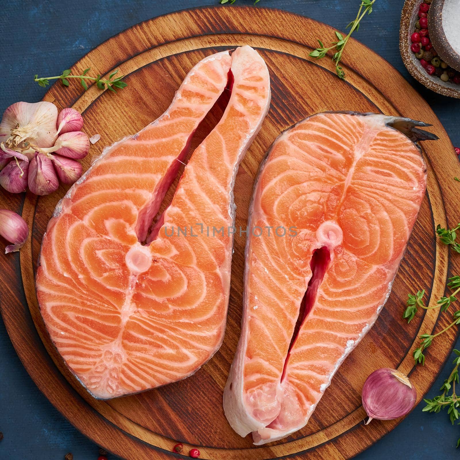Two salmon steaks, fish fillet, large sliced portions on chopping board on dark table. Top view, close up