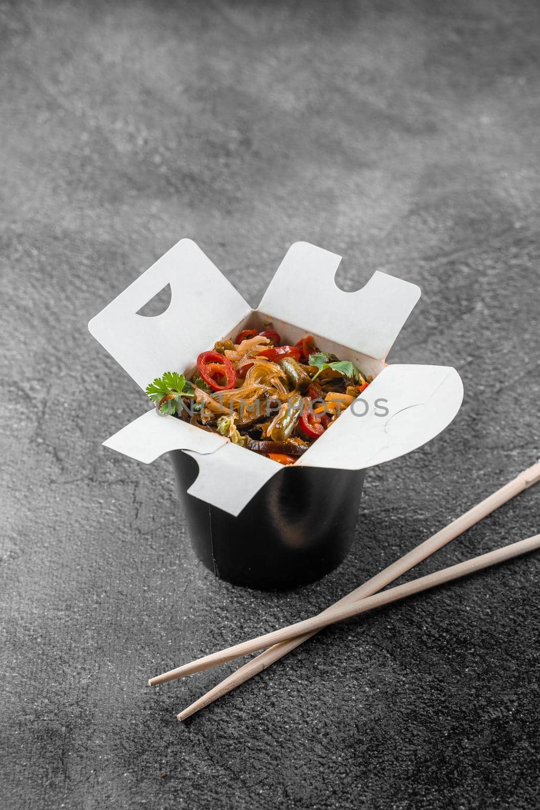 Wok in box rice noodles in black food container. Fast food delivery service. Takeaway chinese street meal. by Rabizo