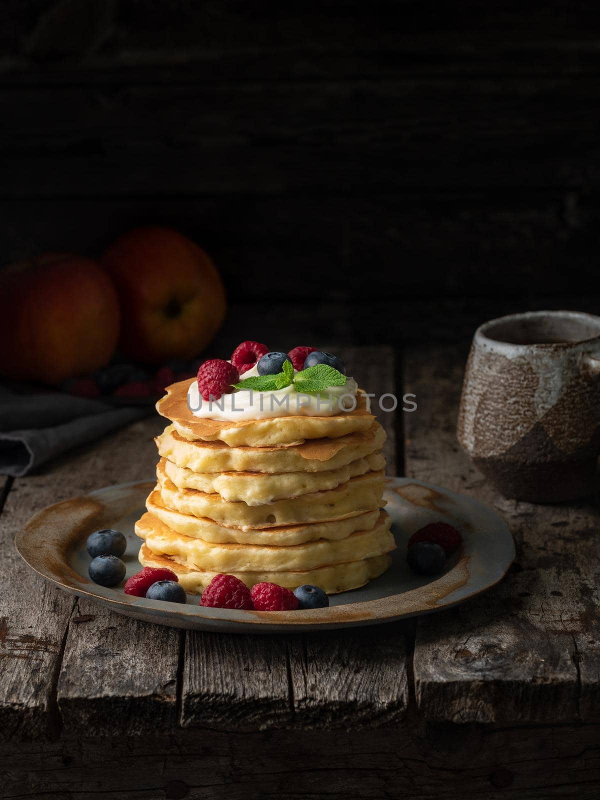 Pancake with vanilla cream, blueberries and raspberries. Side view, vertical, copy space. Dark moody old rustic wooden background. by NataBene