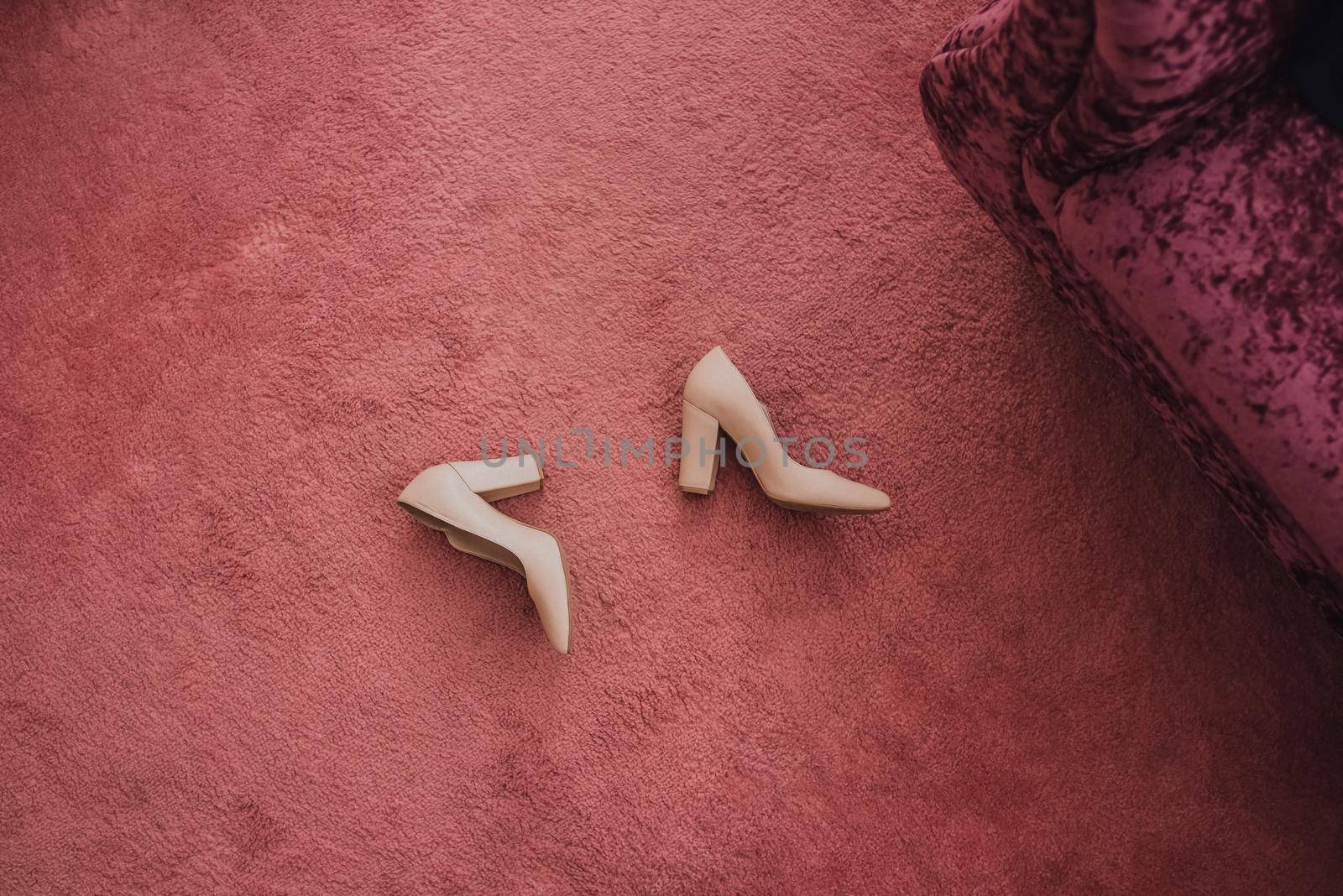 Pink light beige women's high-heeled shoes on the floor on a pink background. classic shoes of the bride