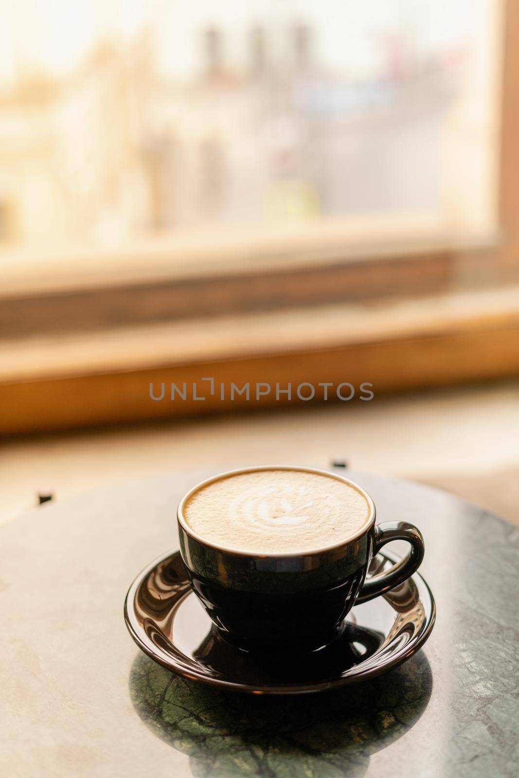 A Cup of cappuccino with foam on a marble table near window in a cozy little cafe. Drink with vegetable milk, oatmeal, coconut by NataBene