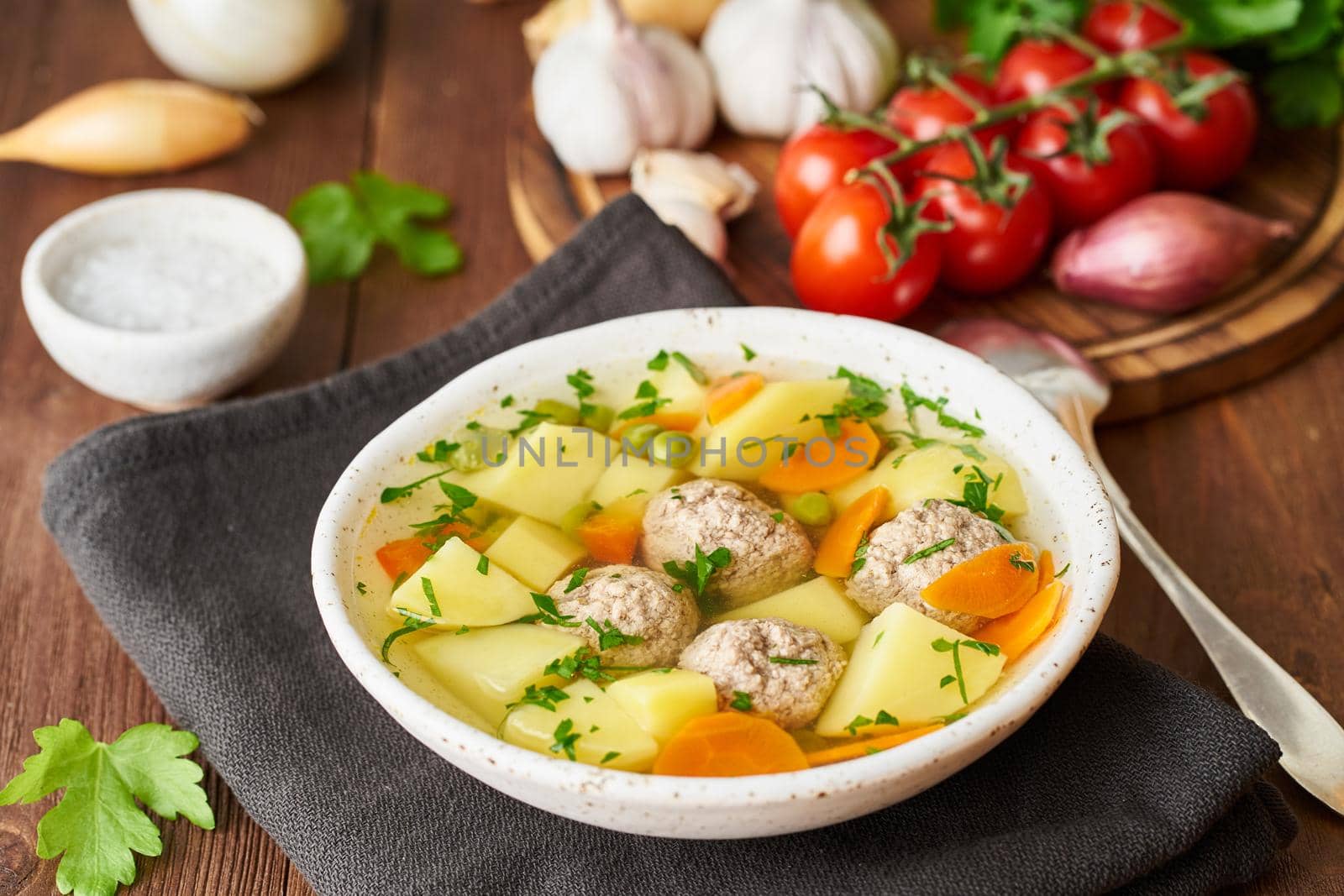 meatballs soup in white plate on old wooden rustic brown table, side view