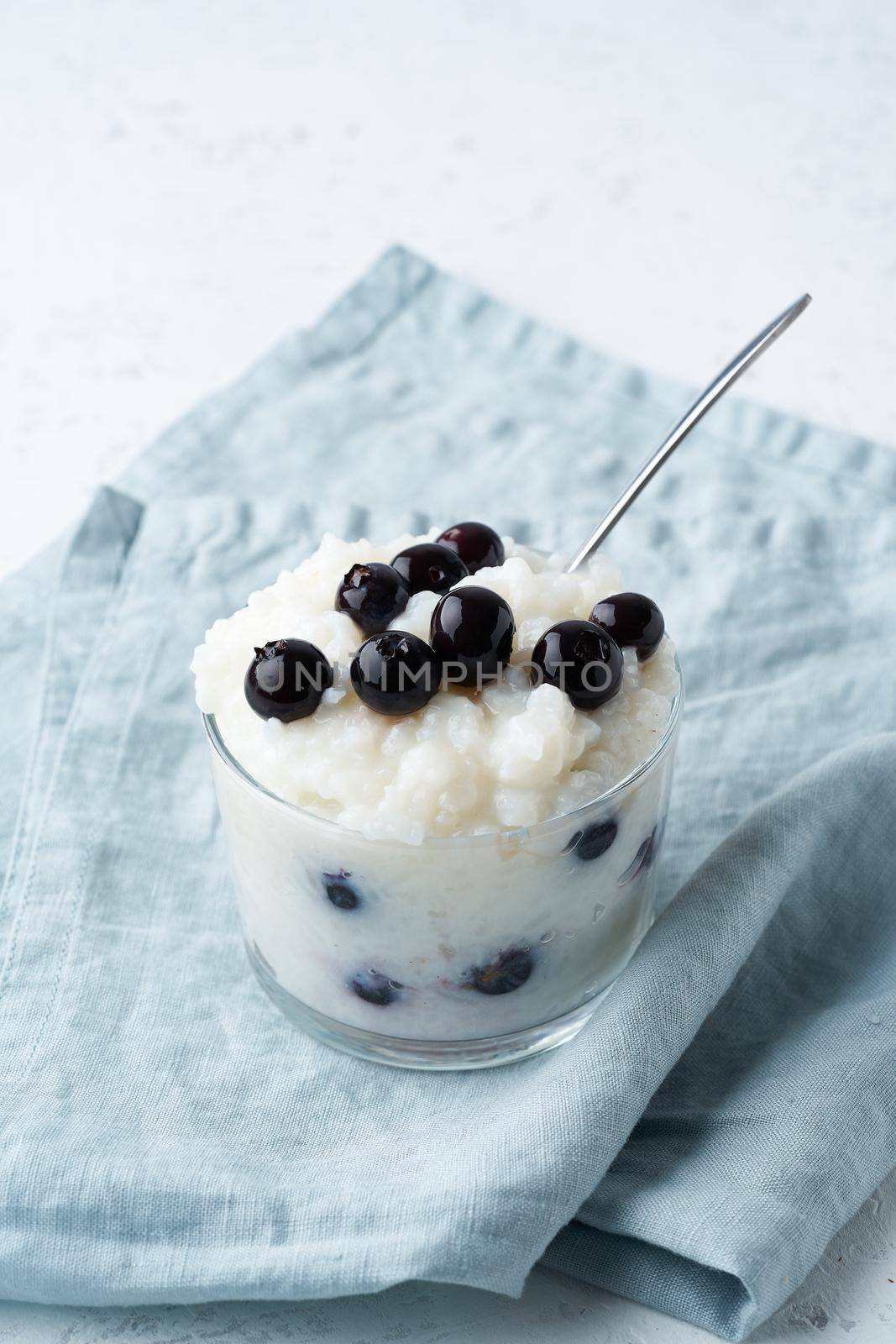 Vegan Coconut Rice Pudding with blueberry, gluten free dessert, side view, vertical. by NataBene