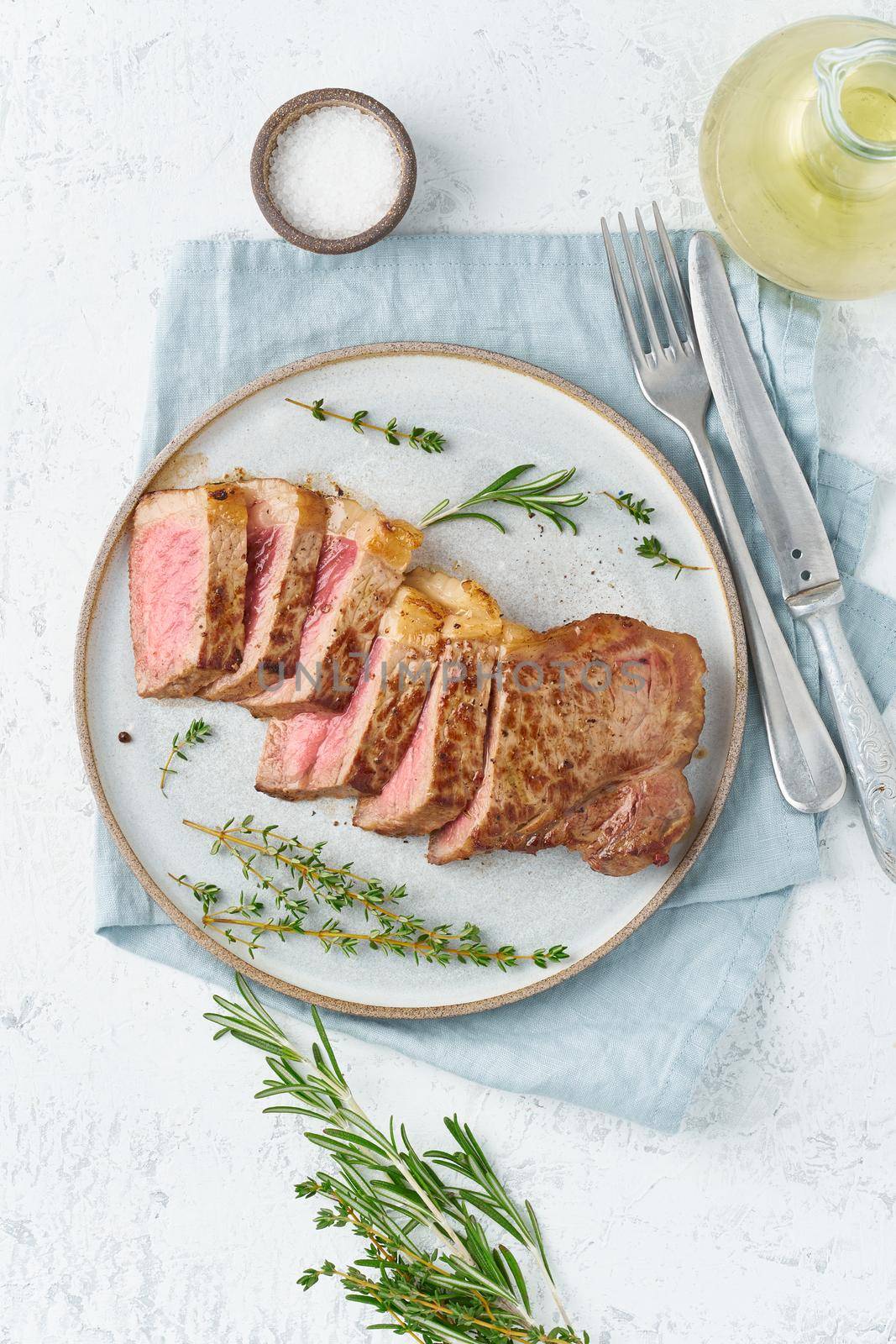 Keto ketogenic diet beef steak, striploin on gray plate on white background. Paleo food recipe by NataBene