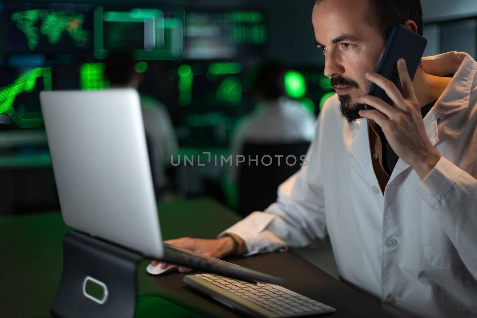 Caucasian male scientist doctor working in the lab using laptop and talking on the phone. by Hoverstock