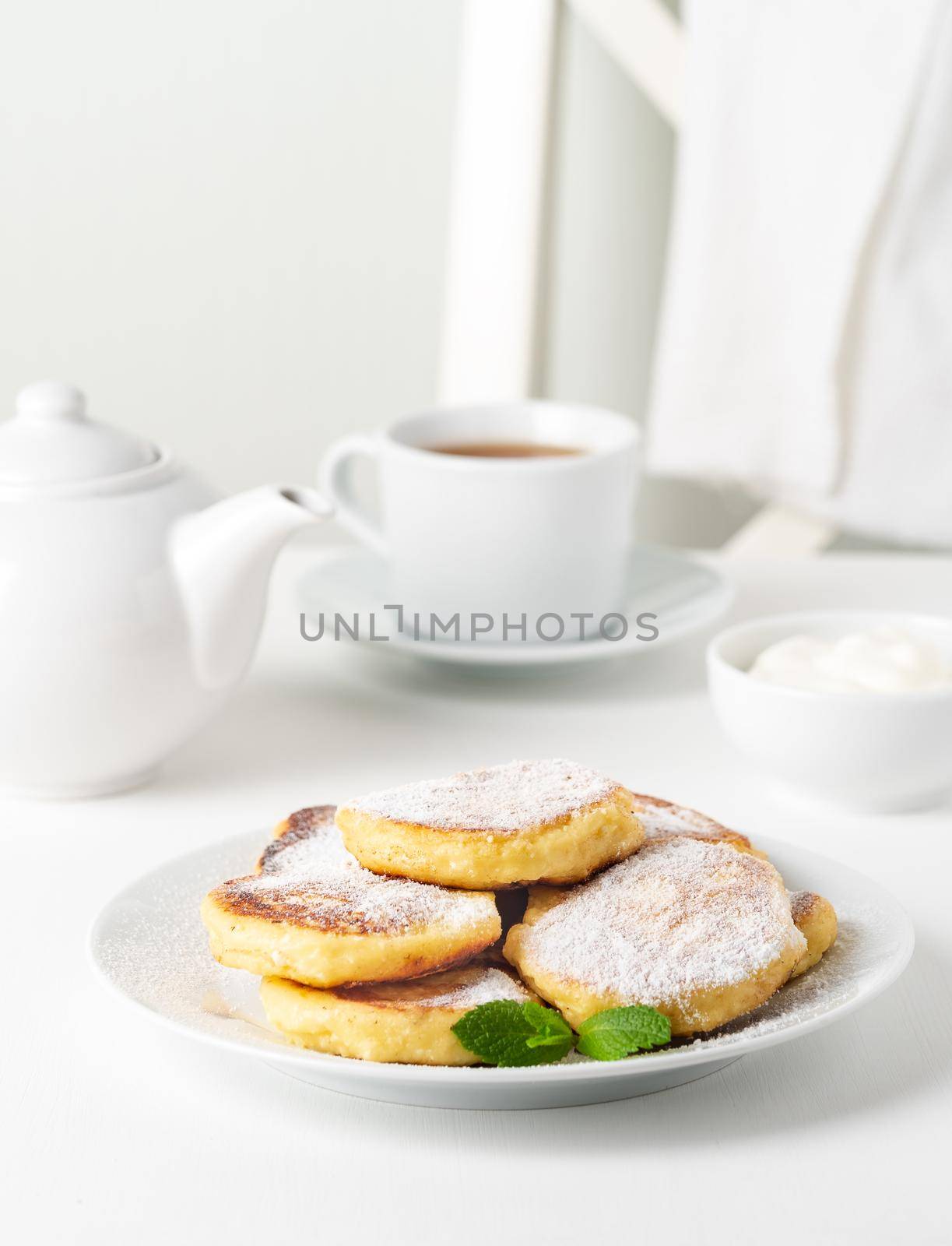 Fried cheese cakes, sweet cheese pancakes on white plate on white background. Home tea party by NataBene