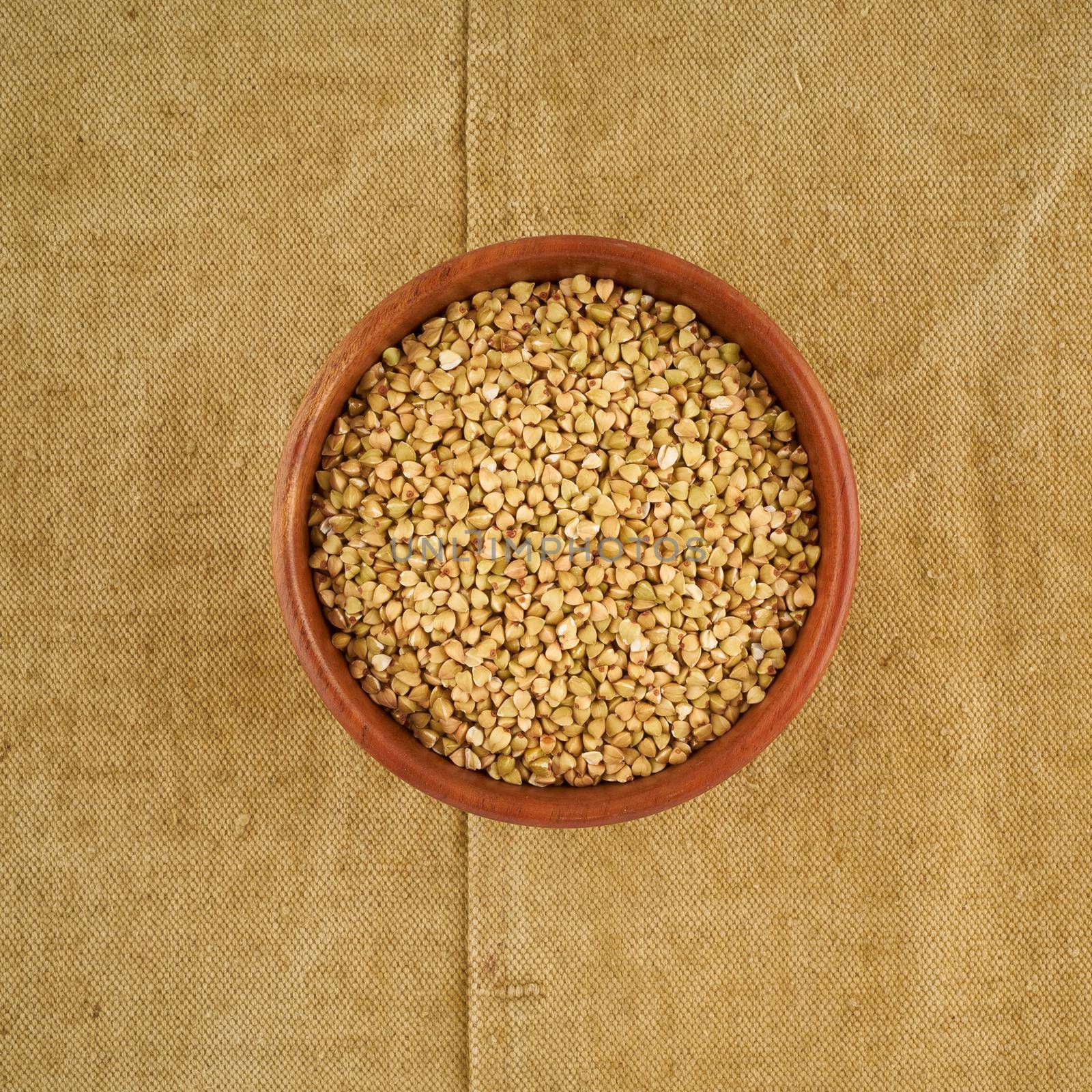 green buckwheat in wooden bowl on old linen napkin, gluten free wholegrain, fodmap diet