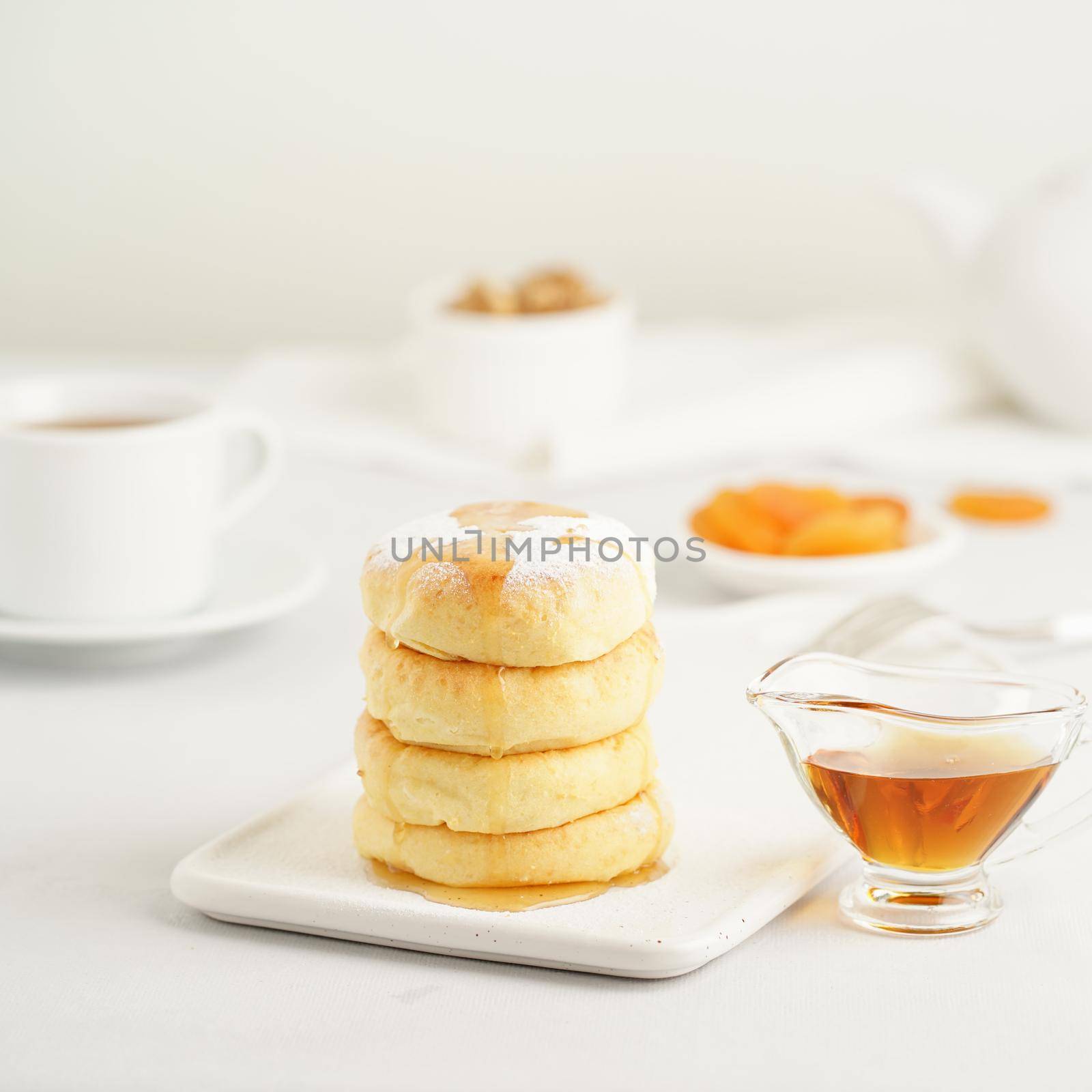Fried cheese cakes, sweet cheese pancakes on white plate on white background. Home tea party