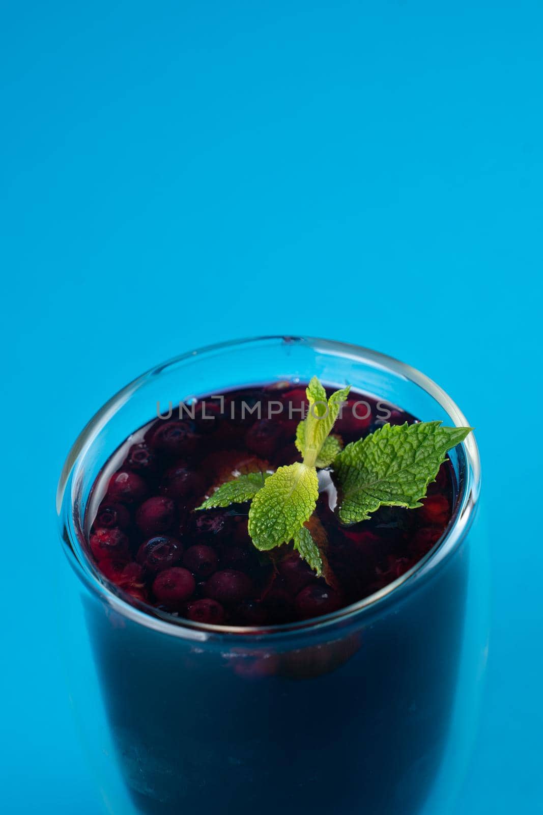 Blueberry tea in double glass cup on blue background.