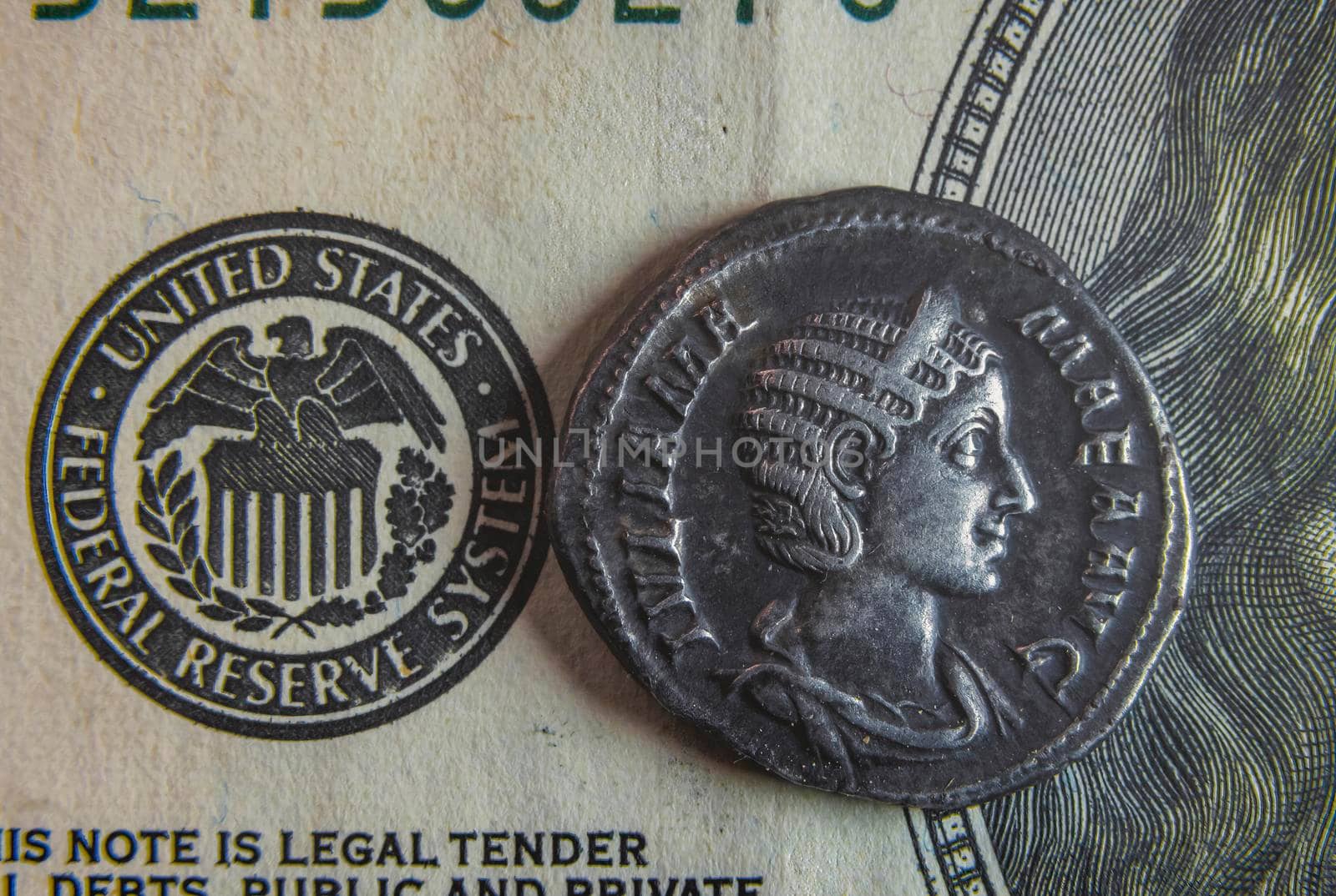 An old Roman coin lies on a 100 dollar bill by zokov