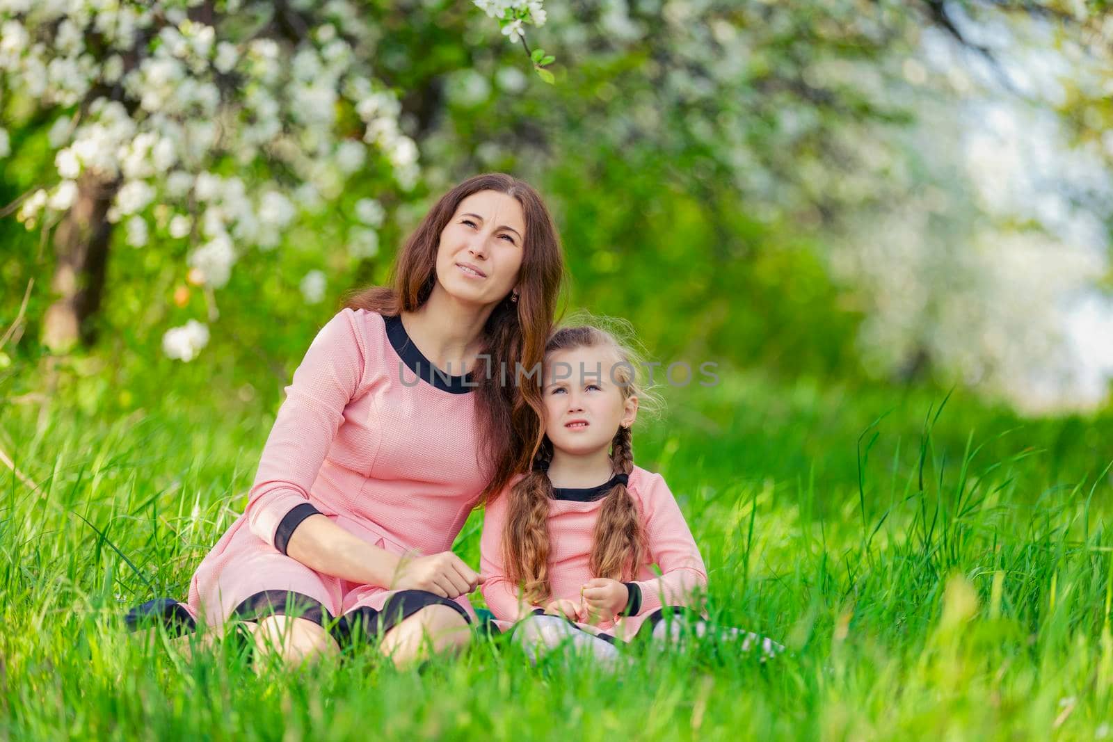 mother and daughter sitting in green grass by zokov