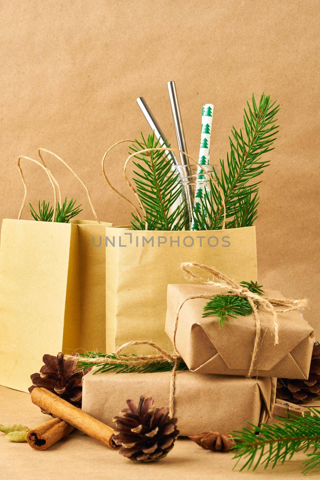 Christmas and Happy New Year zero waste craft paper backdrop. Handmade gift Christmas box, fir branches, reusable straw,, side view, copy space. Ecofriendly plastic free concept, vertical